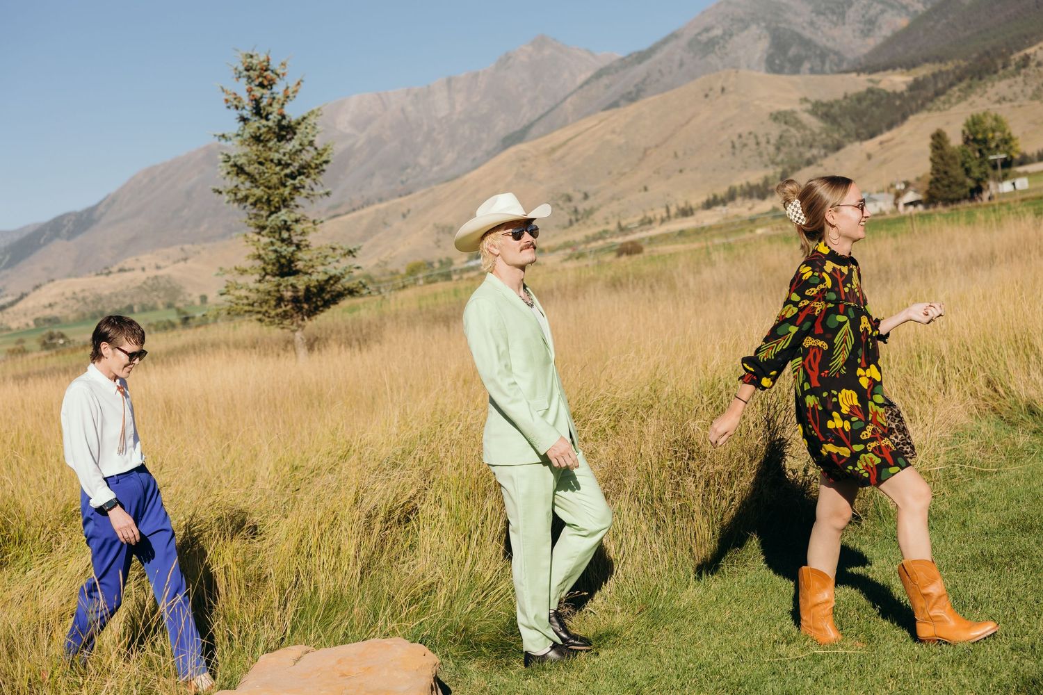 Wedding guests playing outdoor games in mountain field setting.