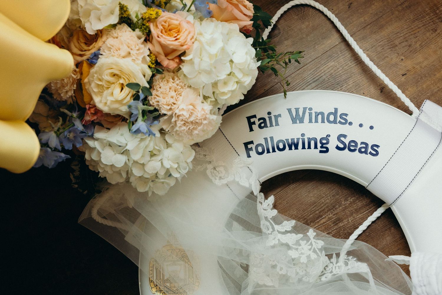 Wedding decor detail showing 'Fair Winds, Following Seas' text with peach and white flowers.