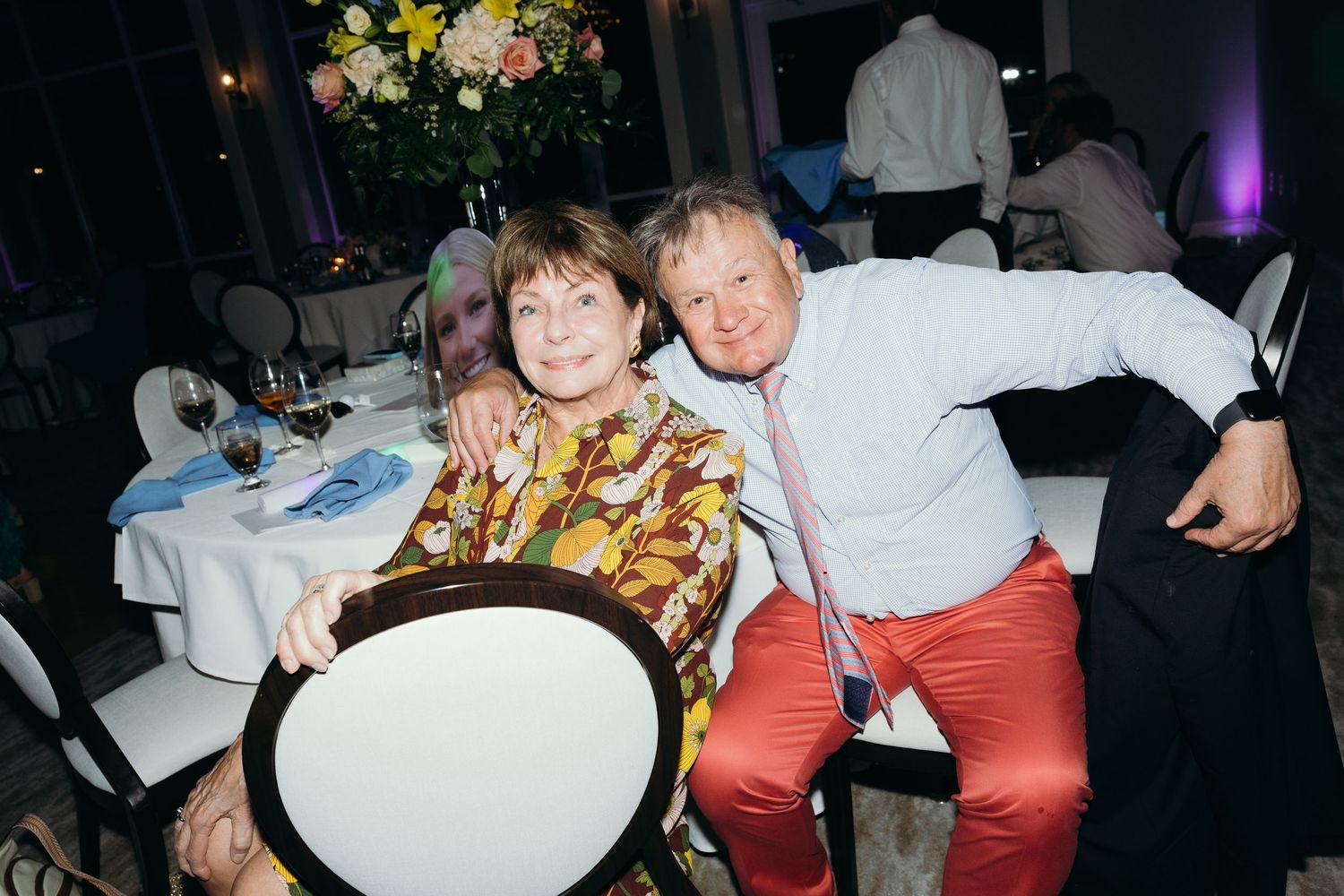 Wedding reception guests enjoying themselves at tables with colorful attire.
