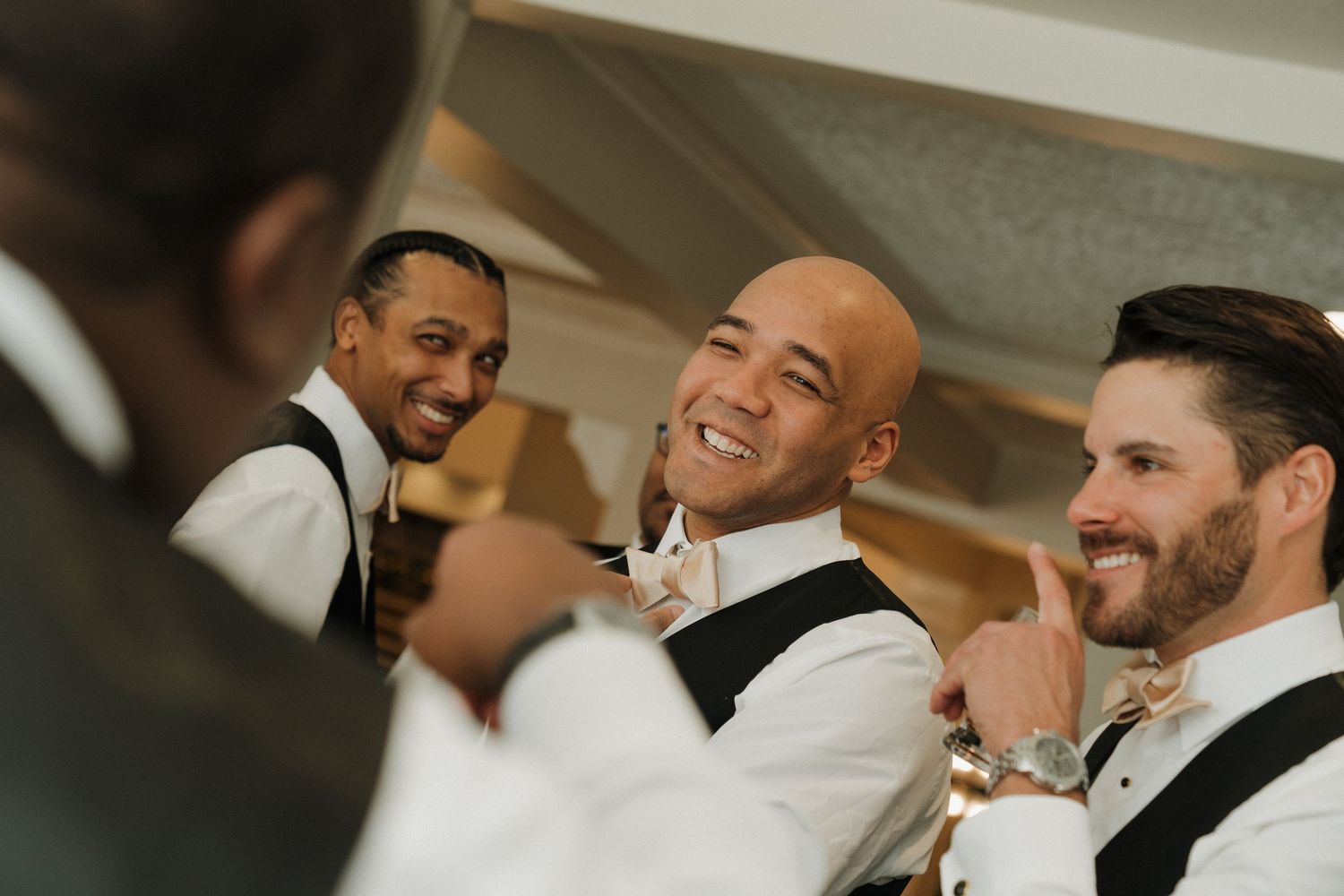 Wedding guests share joyful laughter during a candid moment at the reception.