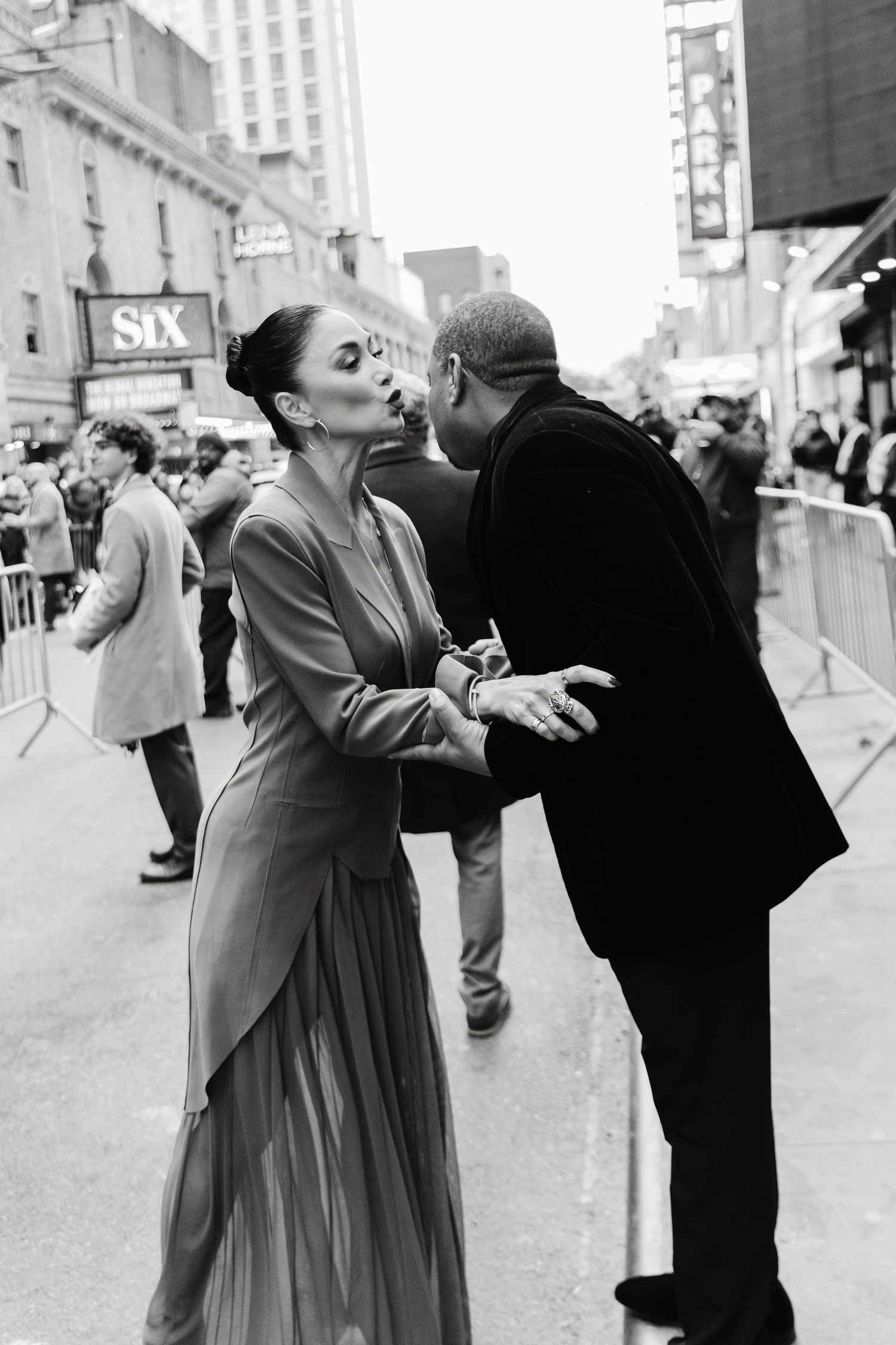 Nicole Scherzinger interacting and embracing at an outdoor event in black and white photography.