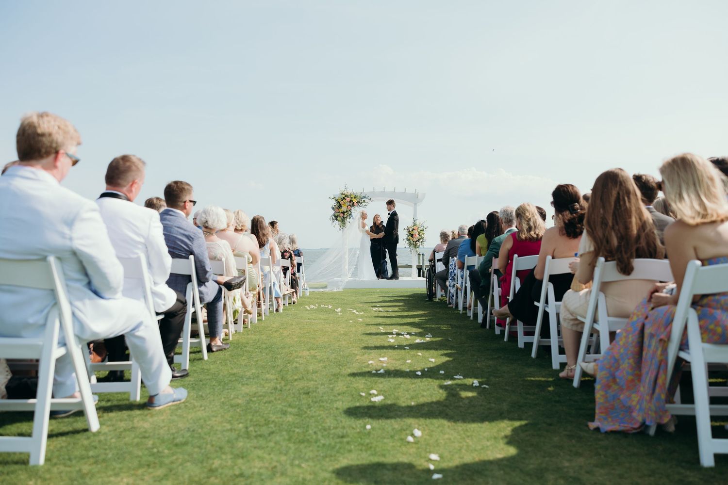 Wedding ceremony setup with white chairs on a grassy hilltop.