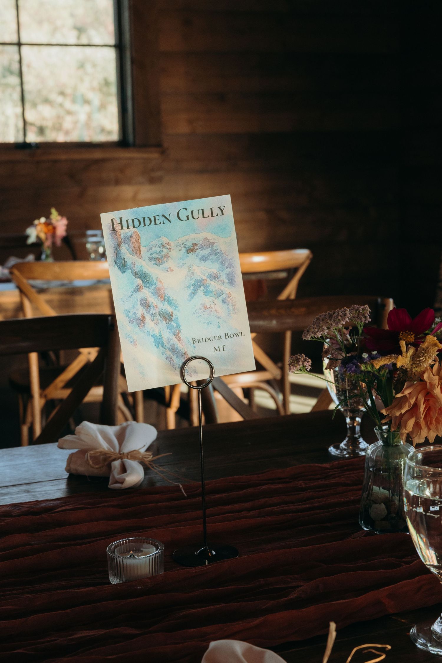 Hidden Gully book display on wooden table with rustic wedding reception decor.
