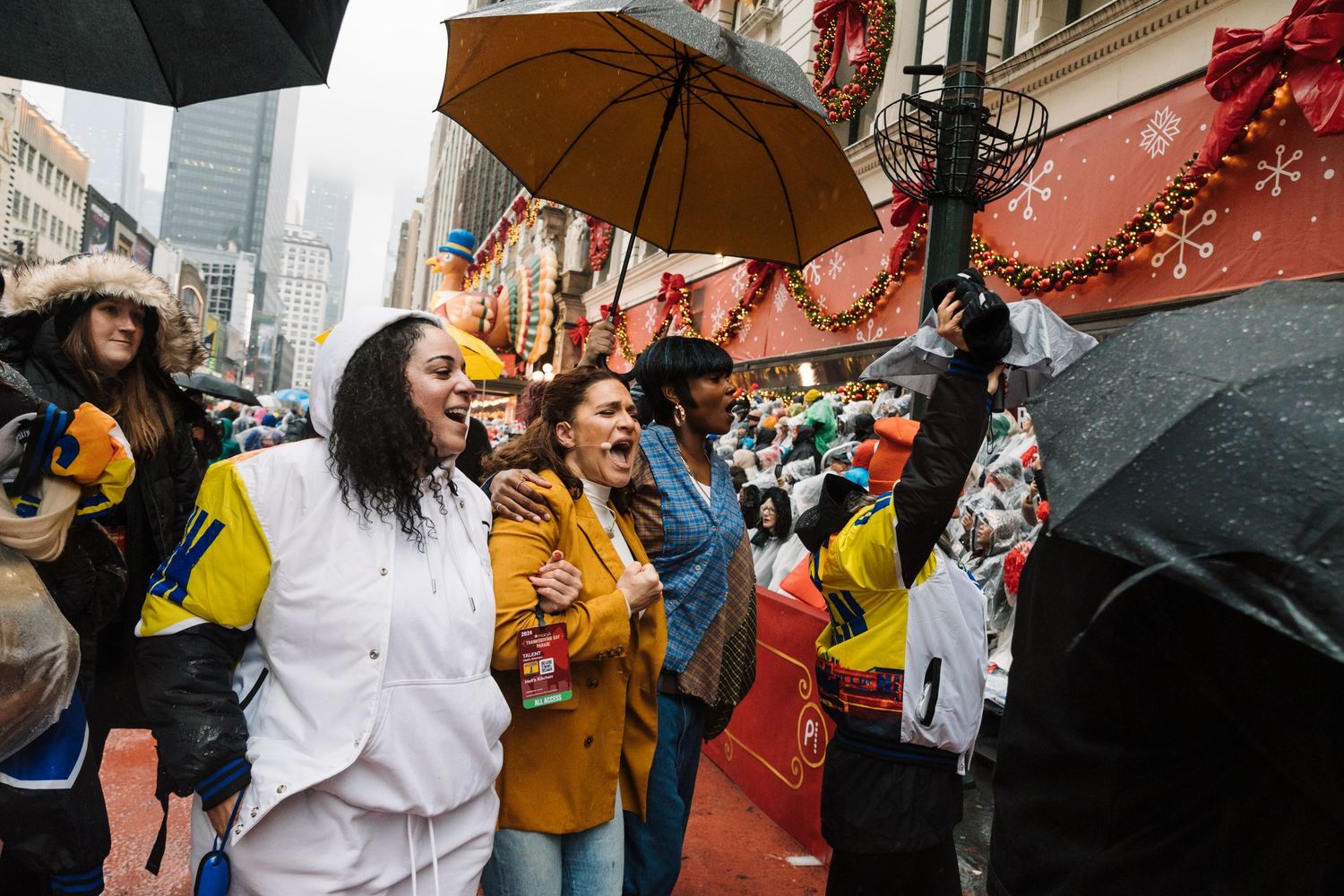 Crowd with umbrellas gathering during rainy holiday celebration on city street.