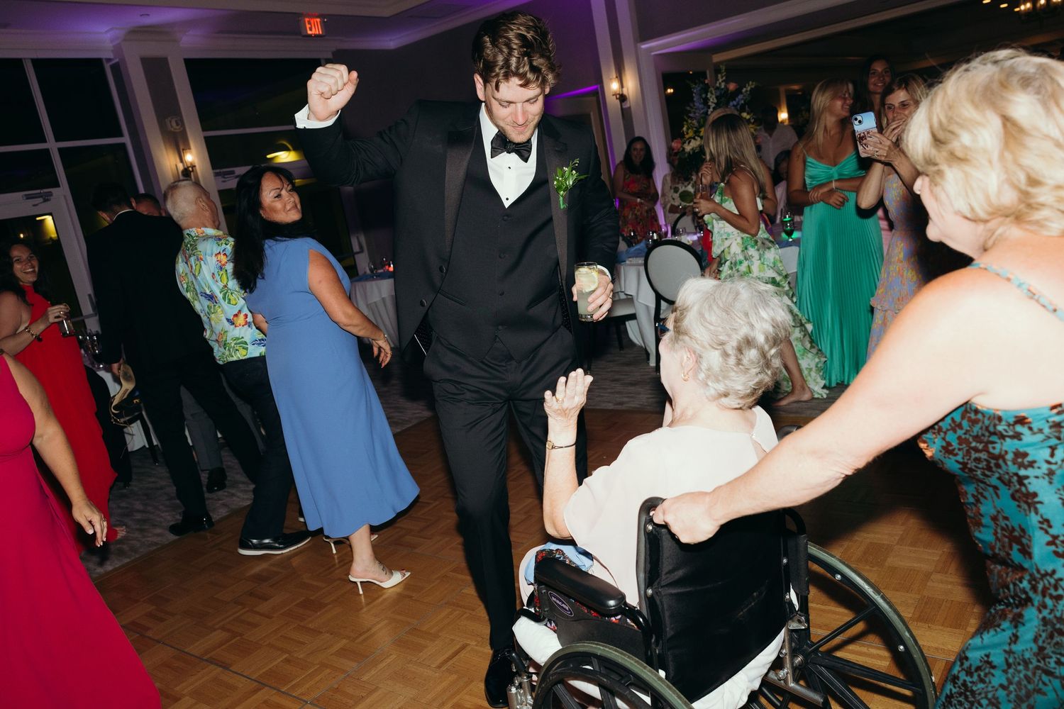 Wedding reception dance floor filled with guests dancing under purple mood lighting.