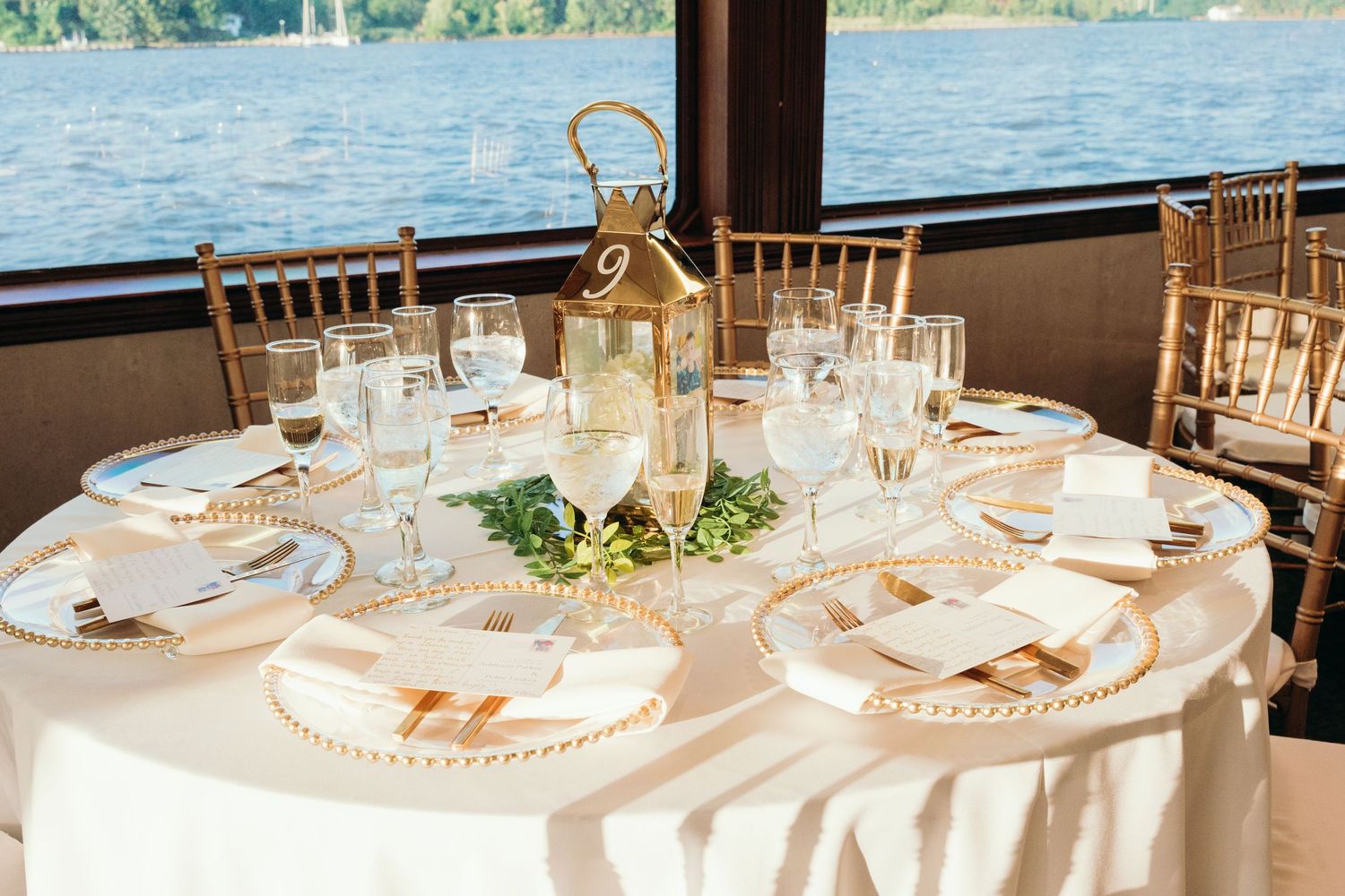 Elegant wedding reception tables set with white linens overlooking a waterfront view.