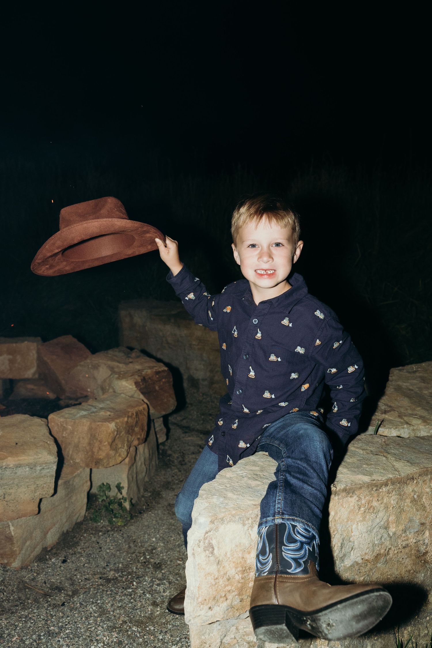 Young child in navy patterned pajamas playing on rocky terrain at night.