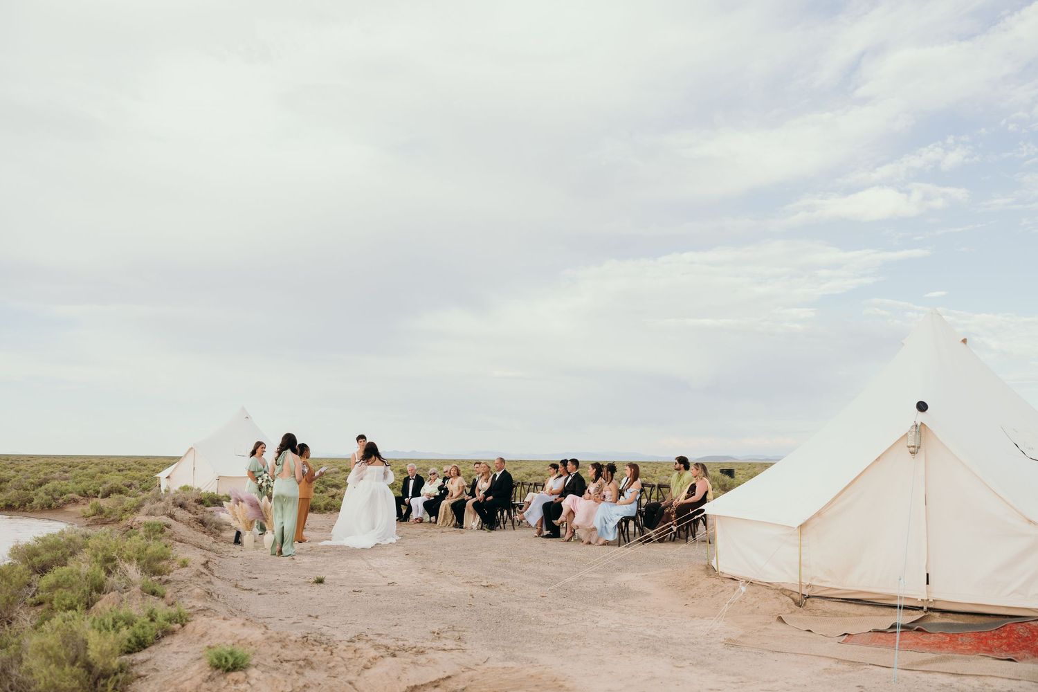 White canvas tents set up in desert landscape for outdoor wedding celebration.