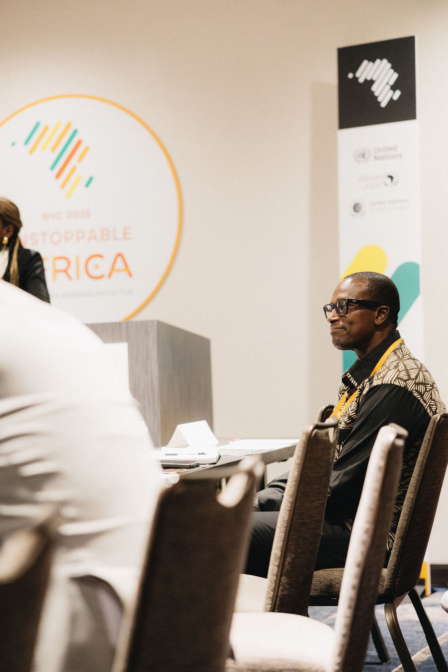 A row of people seated in chairs at a business conference with Africa-themed signage visible in the background.