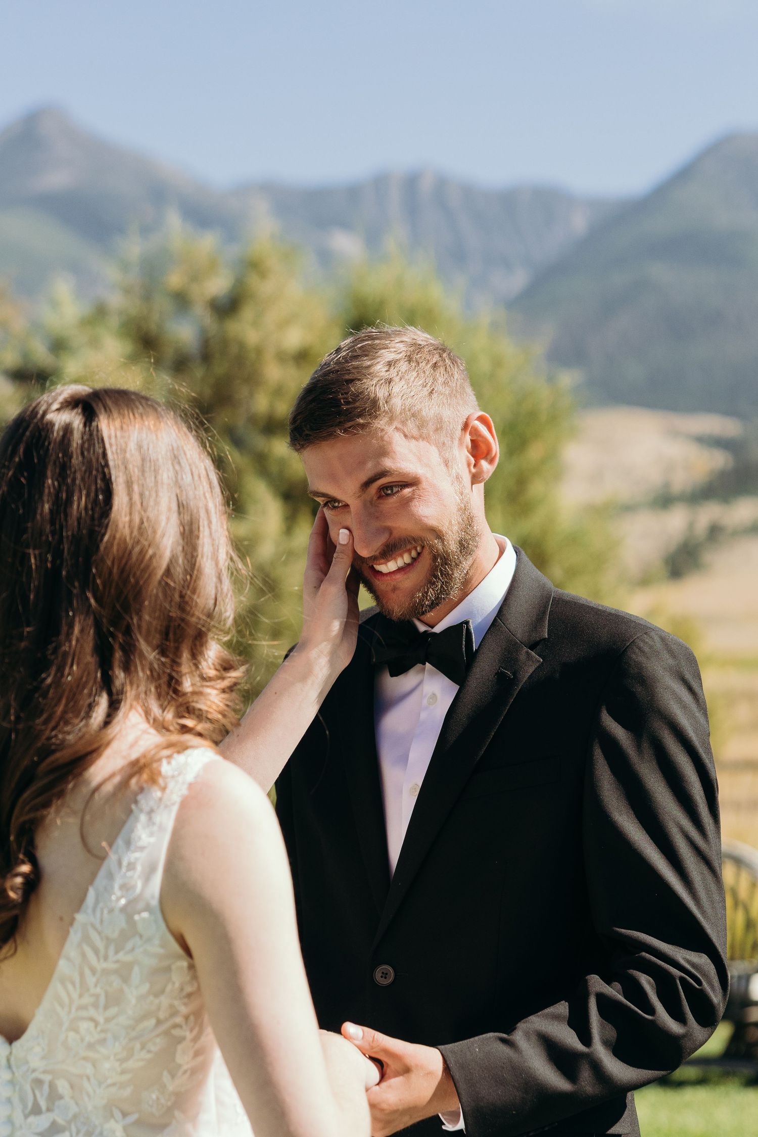 Intimate wedding moment with mountain landscape backdrop during outdoor ceremony.