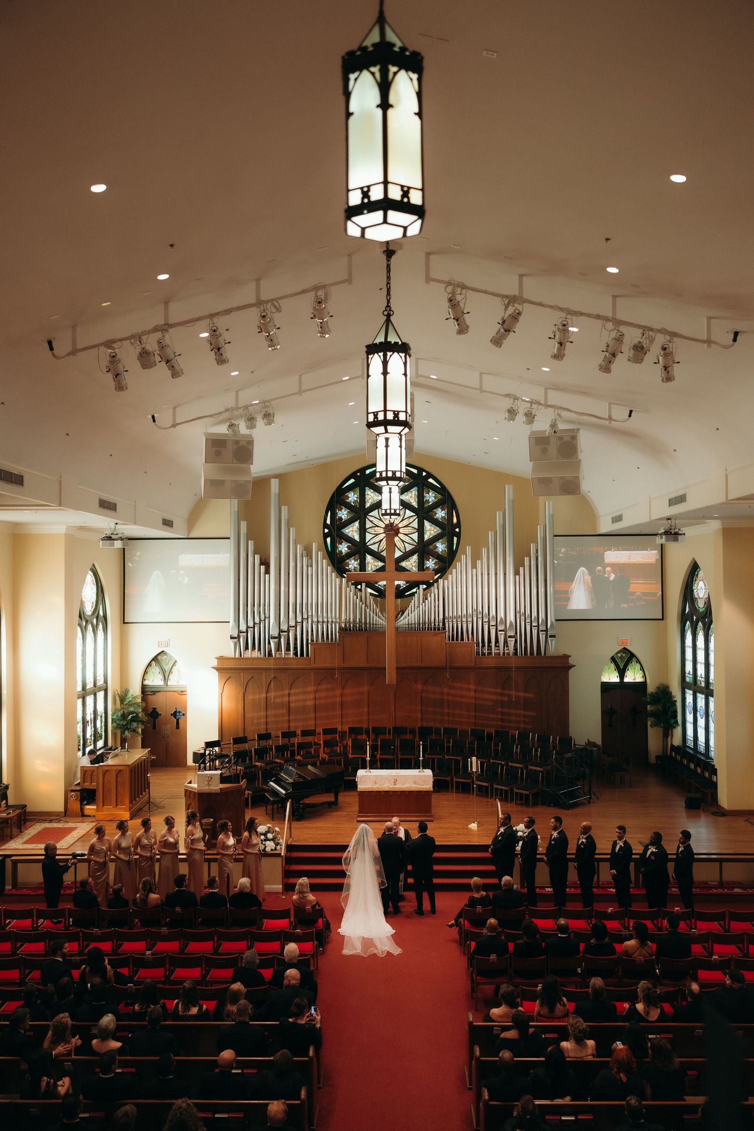 A grand church ceremony with ornate pipe organs and gothic chandeliers illuminating the traditional wedding setting.
