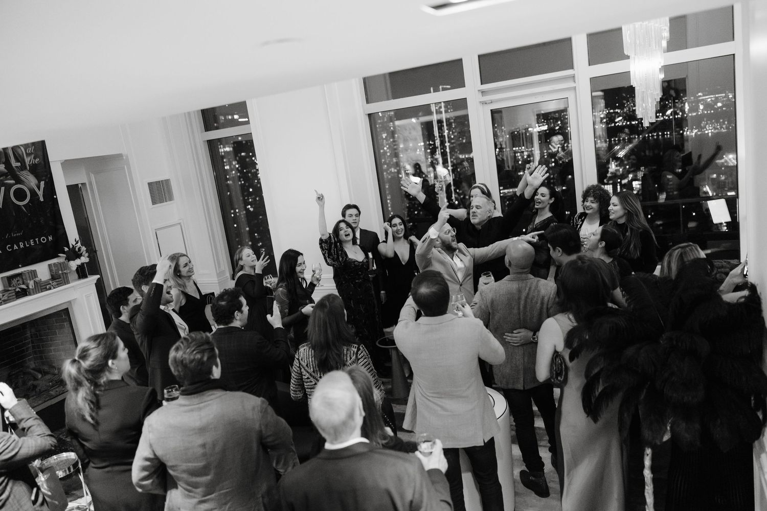 Elegant event space with floor-to-ceiling windows and crystal chandeliers illuminating silhouettes of guests at night for Brisa Carlton