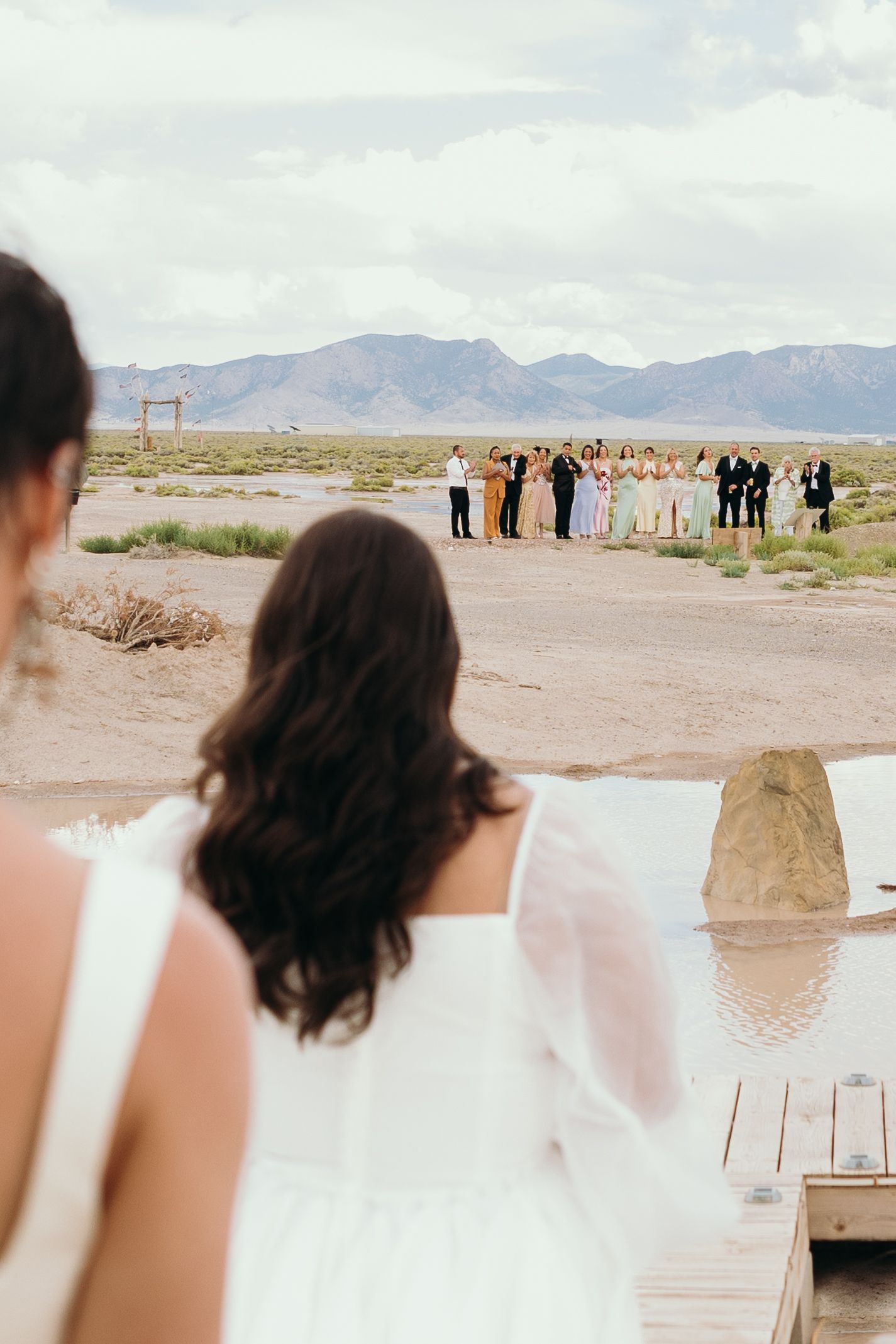Desert wedding ceremony setup with mountain backdrop and gathered guests.
