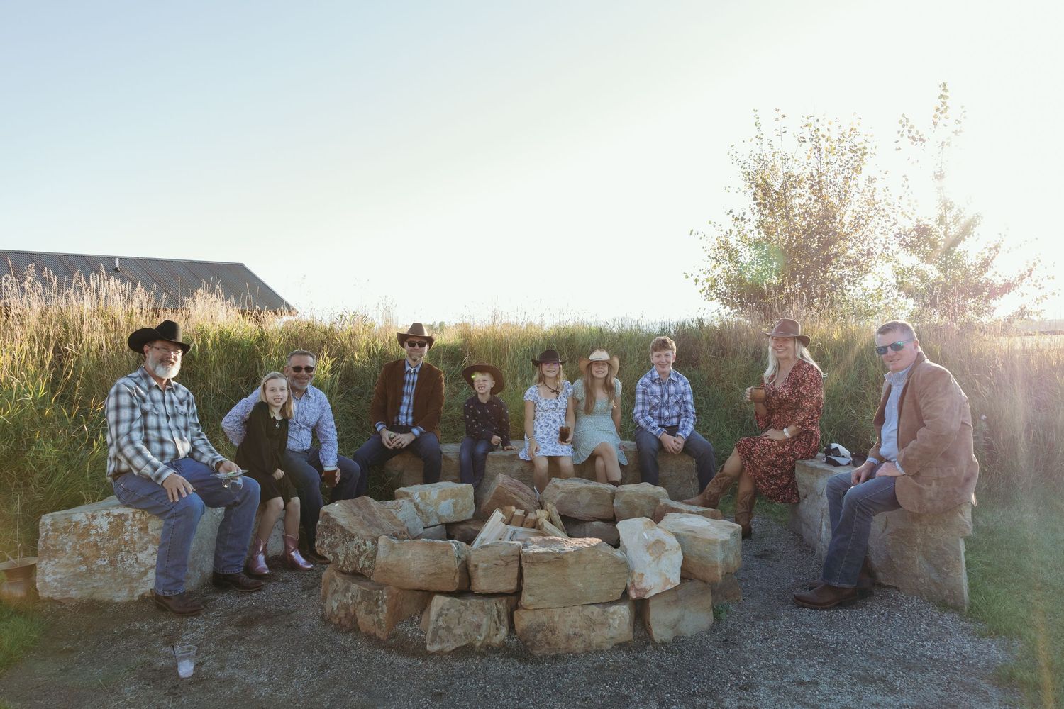 Wedding guests gathered on stone benches for outdoor group photos at sunset.