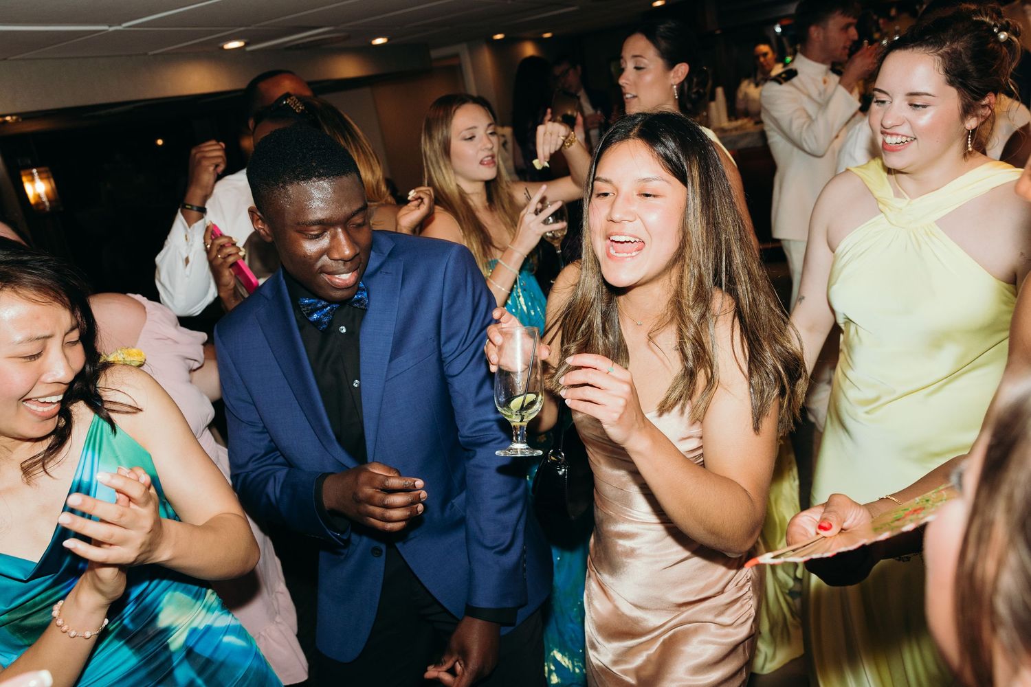 Wedding guests in formal attire dancing and celebrating at an indoor reception.