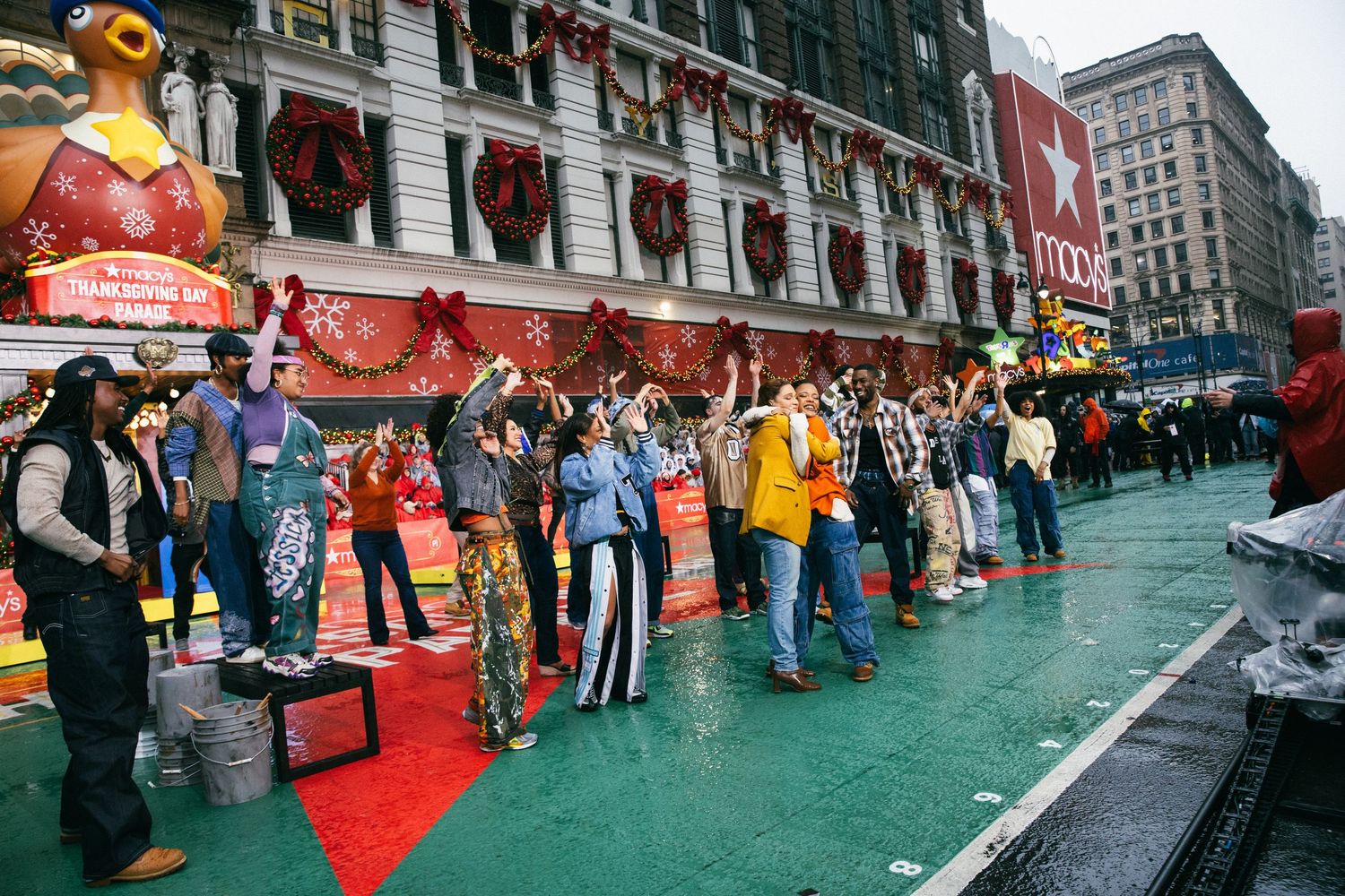 Crowd of people lined up on green street surface outside decorated storefront during holiday event.