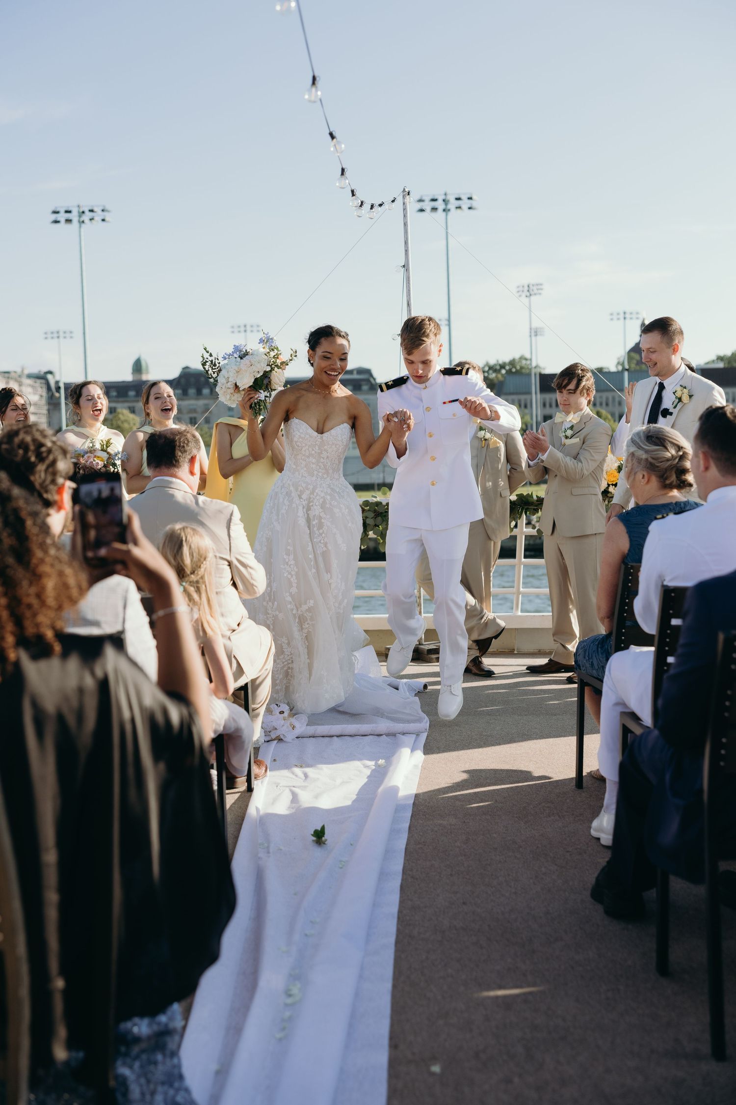 Wedding party celebrates on an outdoor deck during a sunny afternoon reception.