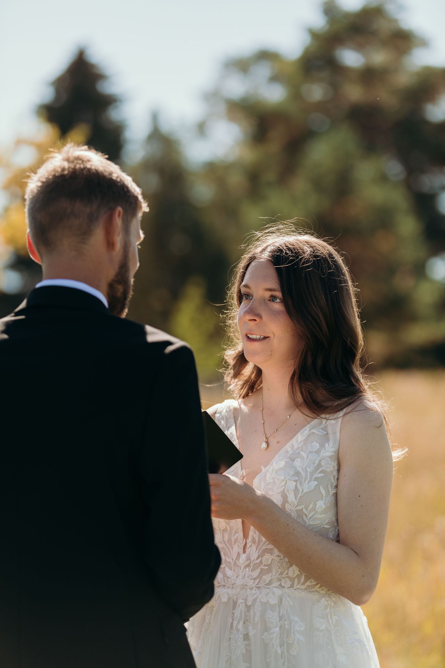 A wedding couple shares an intimate moment in a sun-drenched field during their ceremony.