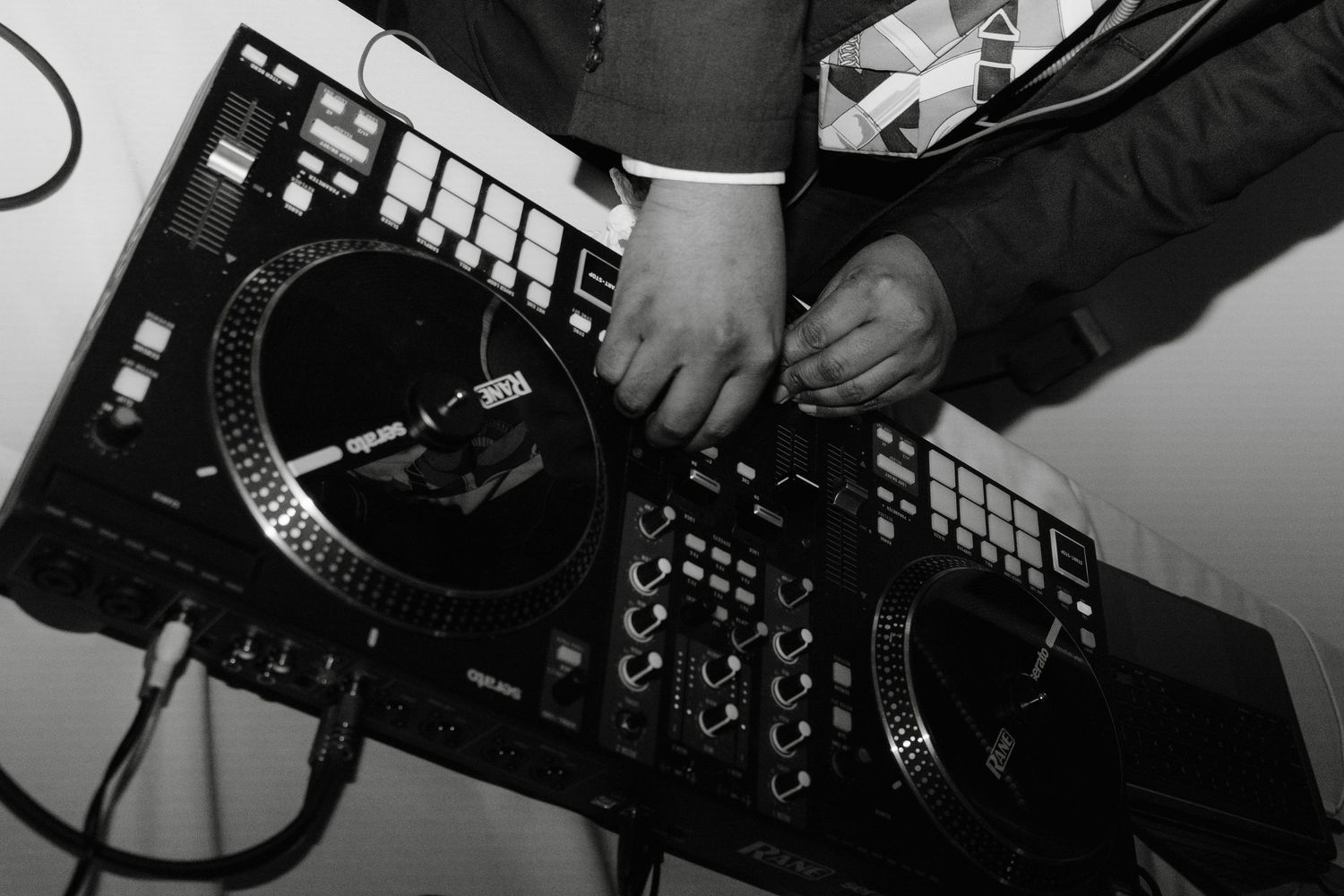 Close-up black and white shot of DJ hands working on professional mixing equipment.