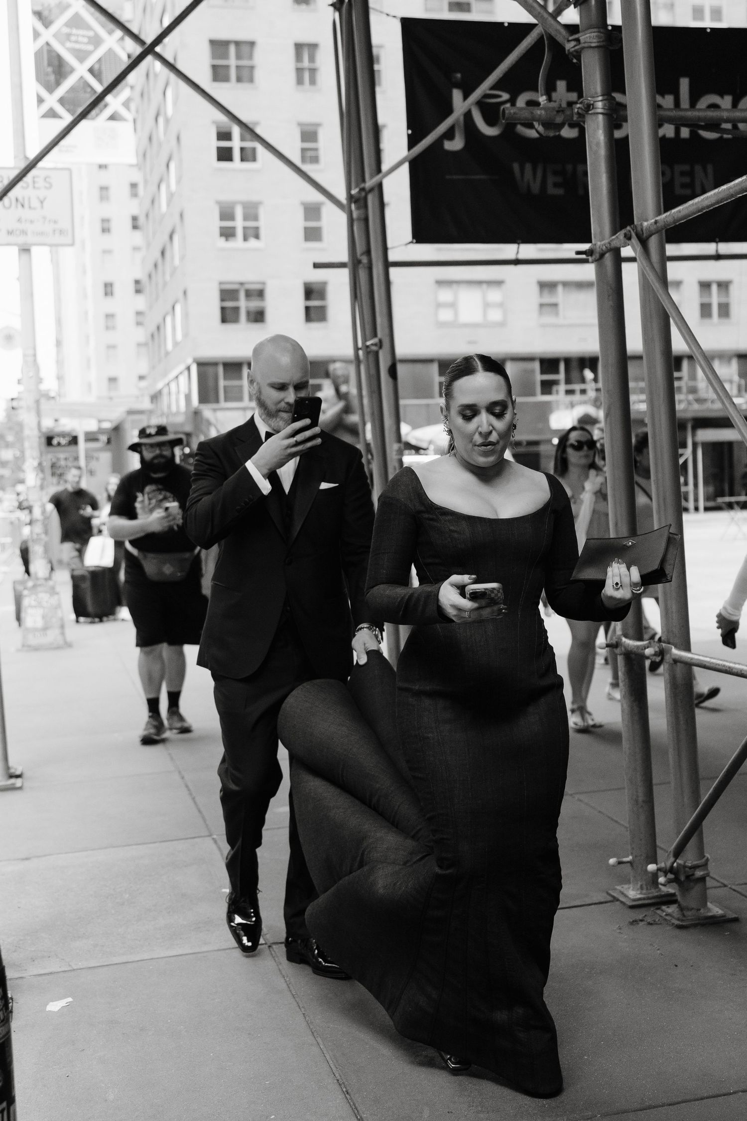 Urban street scene with pedestrians walking past storefronts and scaffolding in black and white photography with Jessica Vosk and Dave