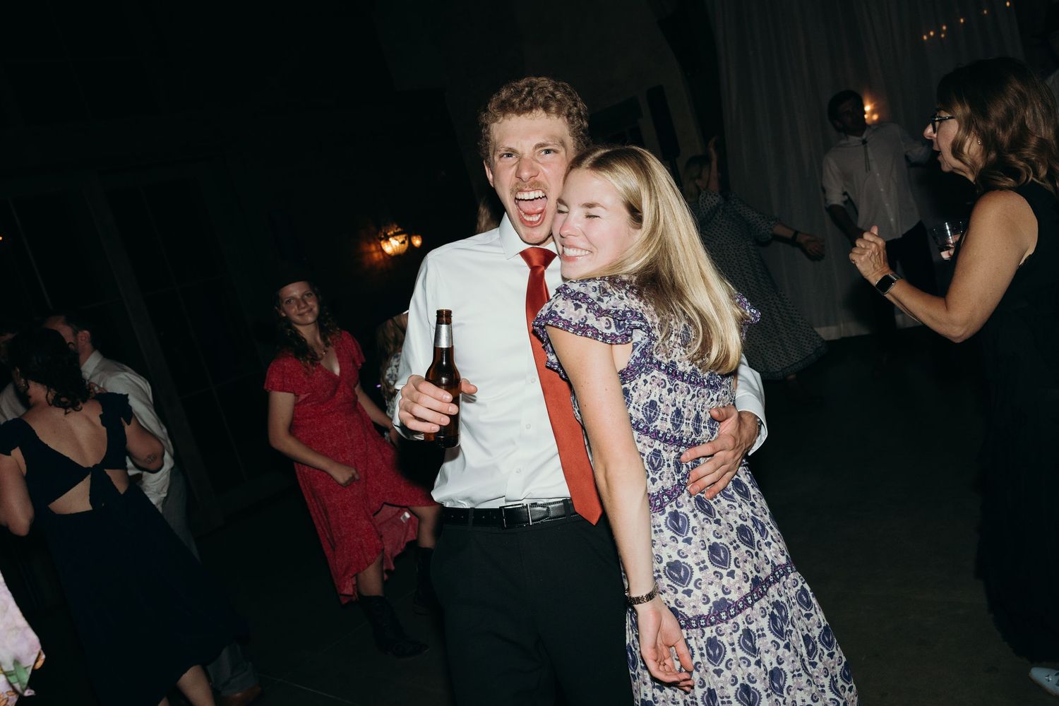 People enjoying themselves on a dark dance floor at a celebration.