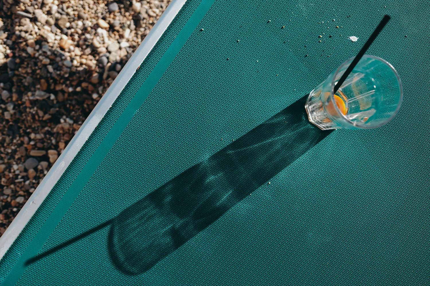Glass bottle casting dramatic shadows against a turquoise background in multiple artistic compositions.