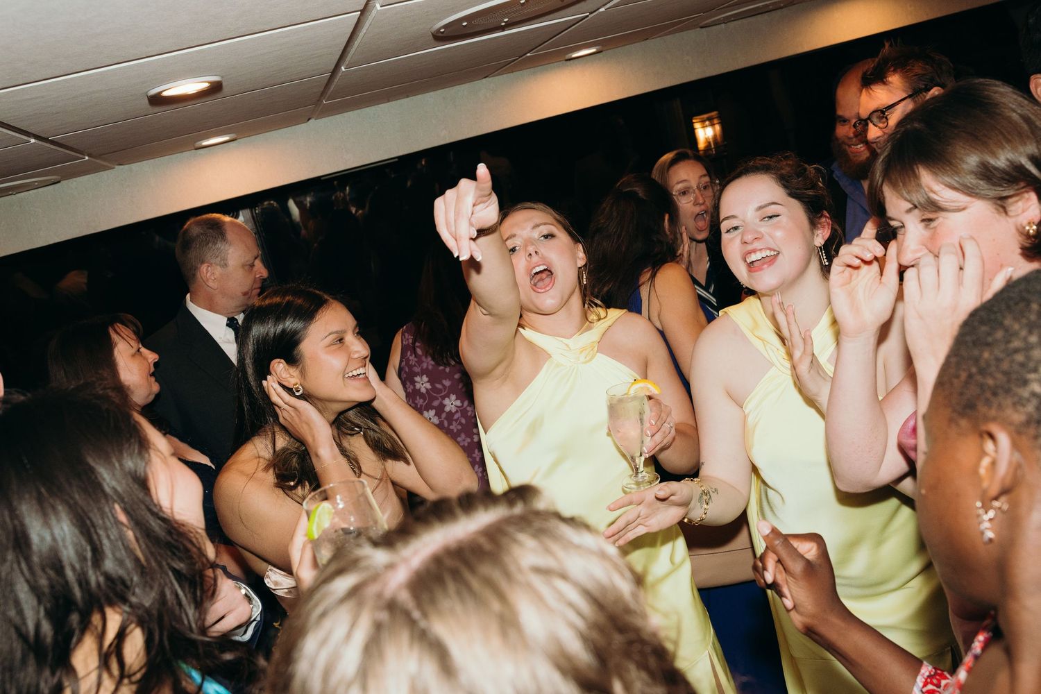 Wedding guests dancing and celebrating energetically on a crowded dance floor at a reception party.