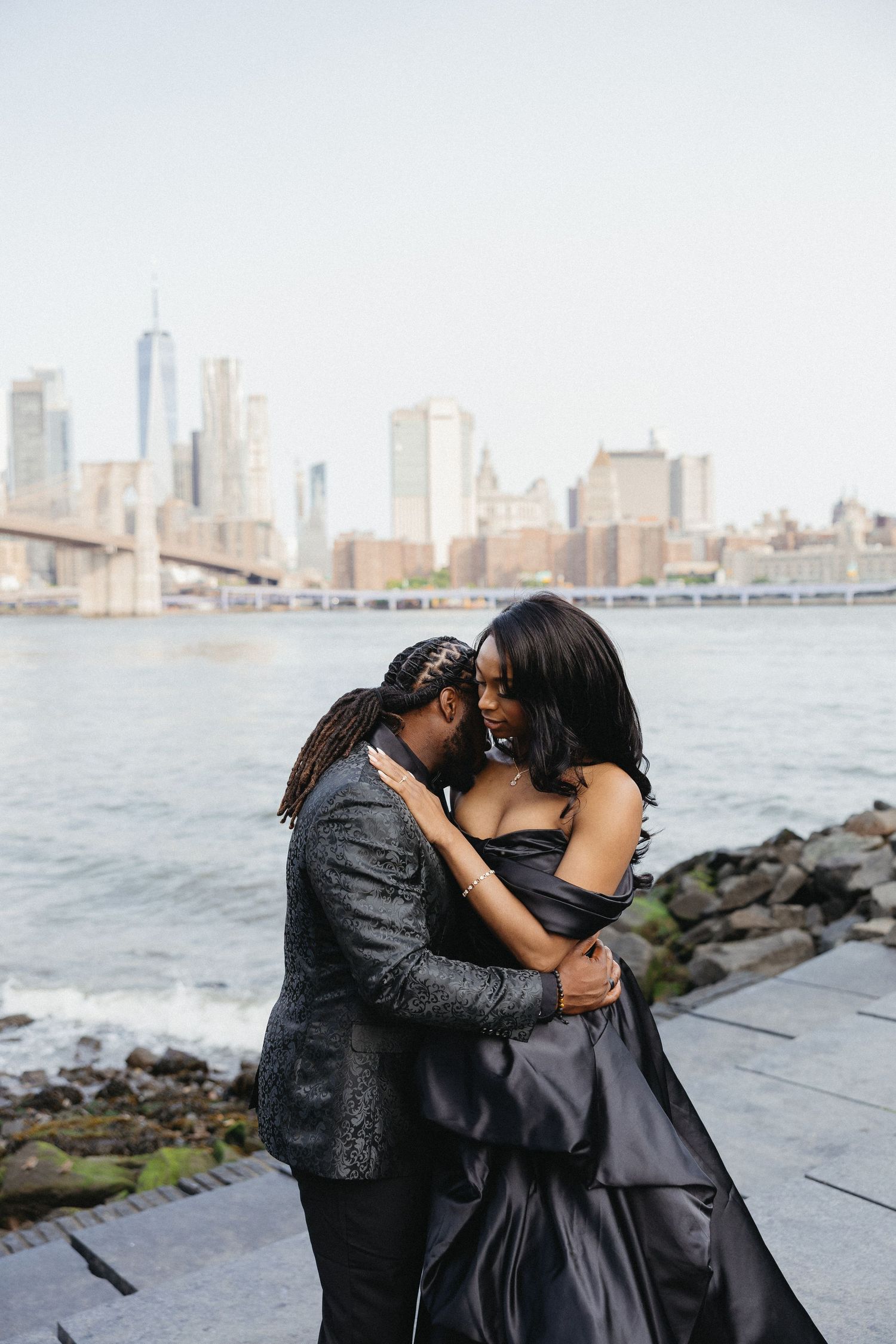 Urban waterfront engagement photoshoot with city skyline backdrop.