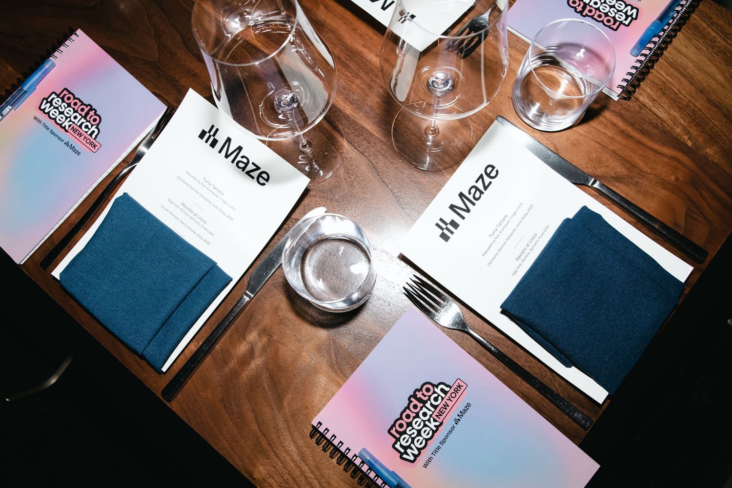 Wine glasses and menus arranged on a rustic wooden table in a restaurant setting.