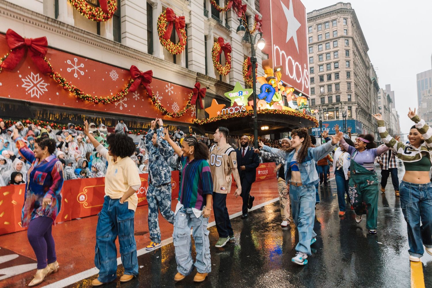 People queue outside a department store decorated with holiday ornaments in the rain.