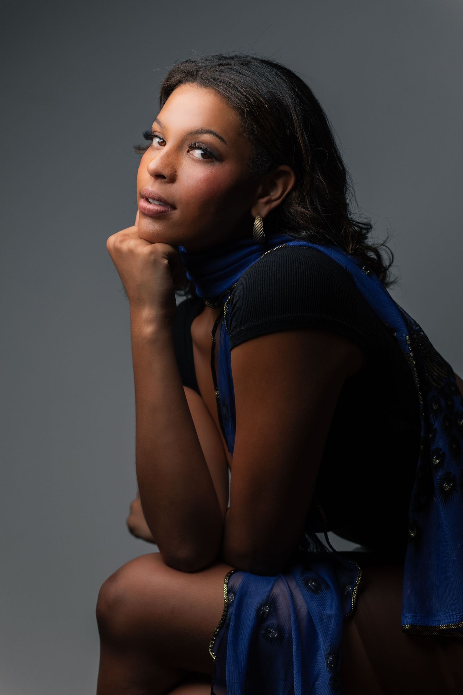 A dramatic portrait series against gray background featuring dark skin tones and deep blue fabric accents.