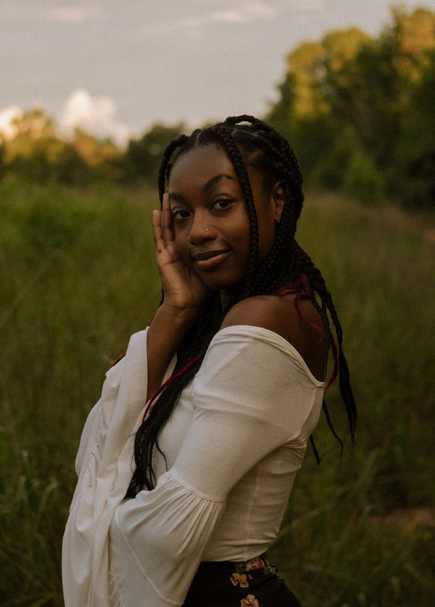 Photo of a senior girl standing in a field at golden hour