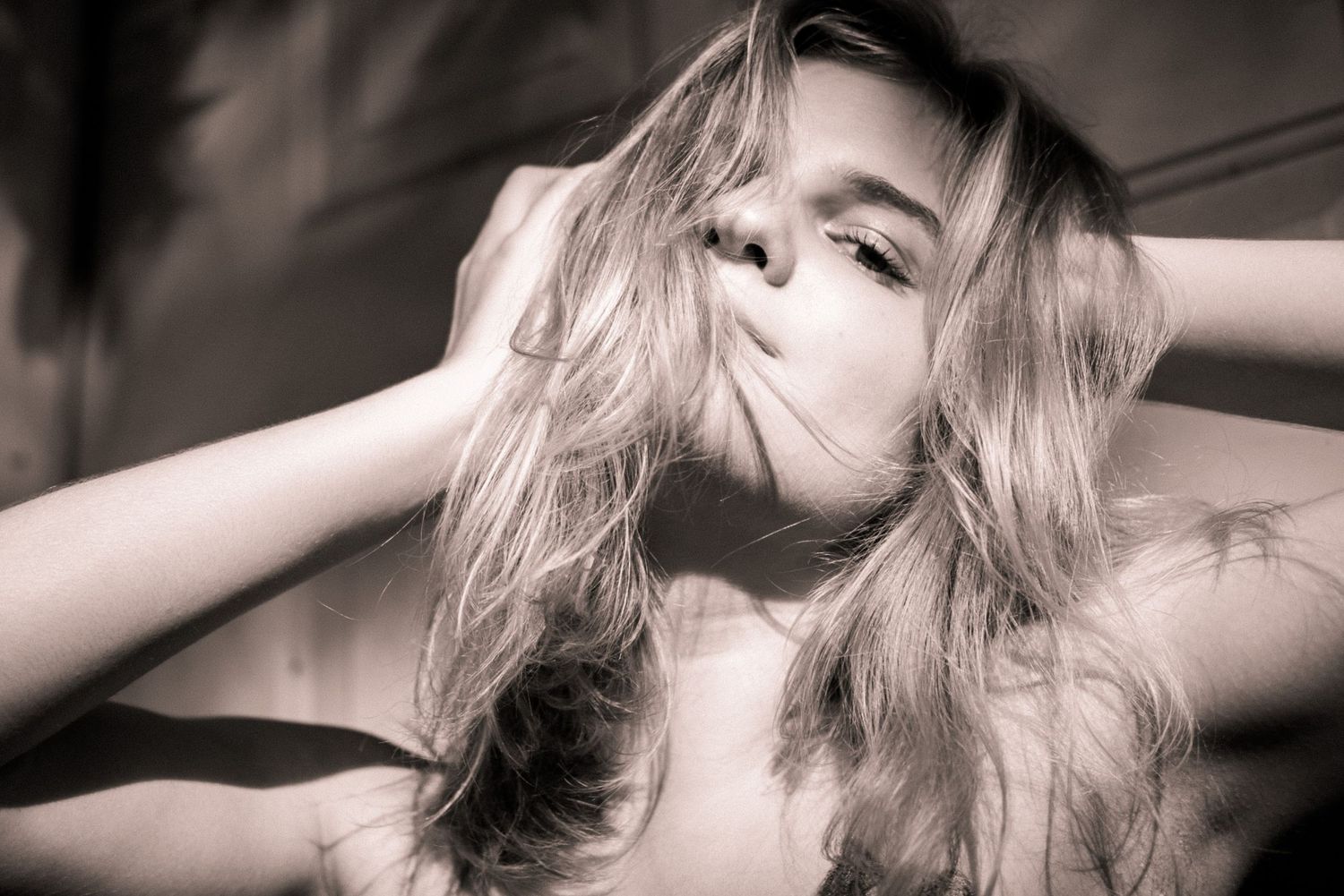 Black and white photo of a girl pulling her hair in sunlight