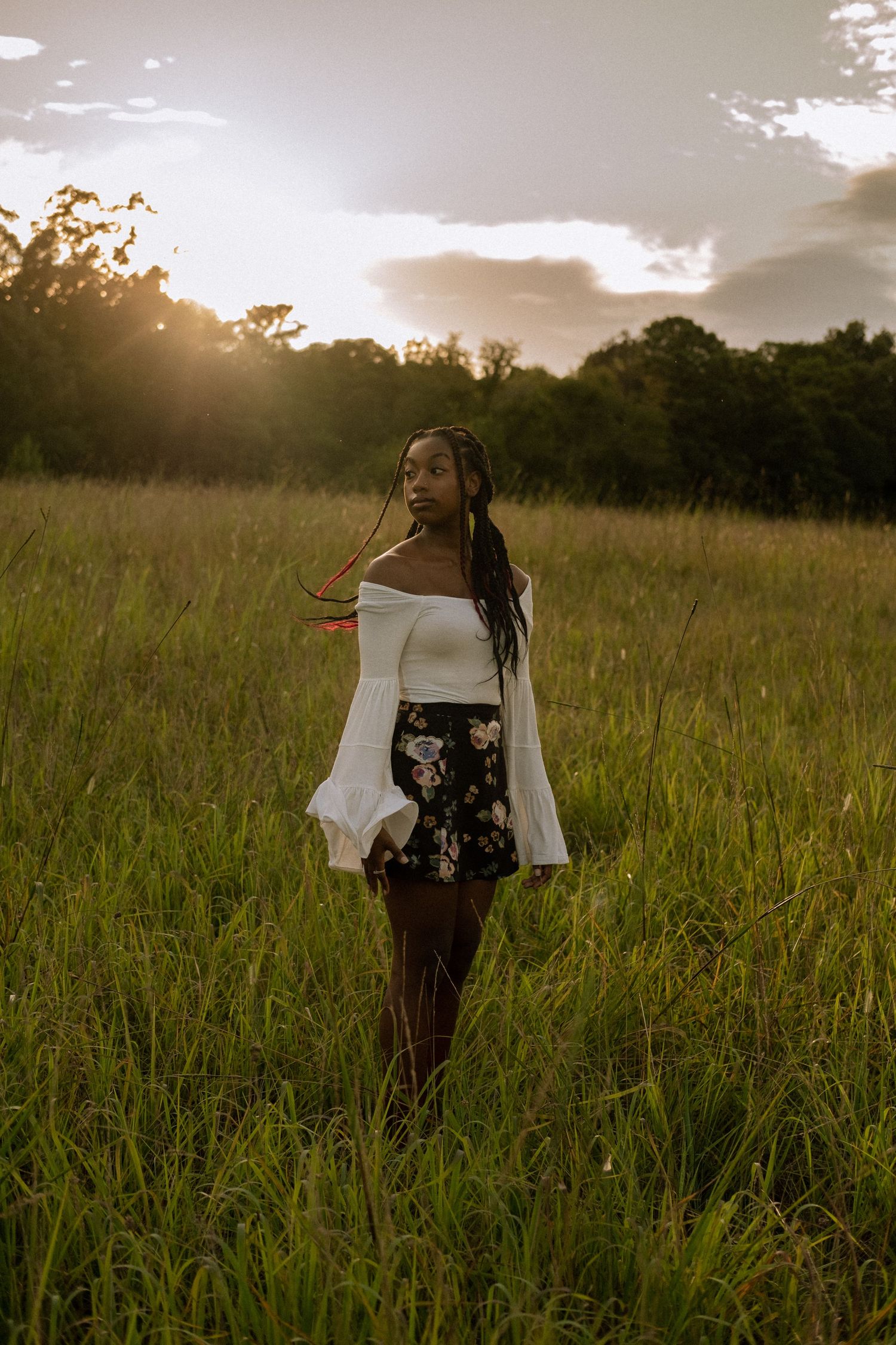 Photo of a senior girl standing in a field at golden hour