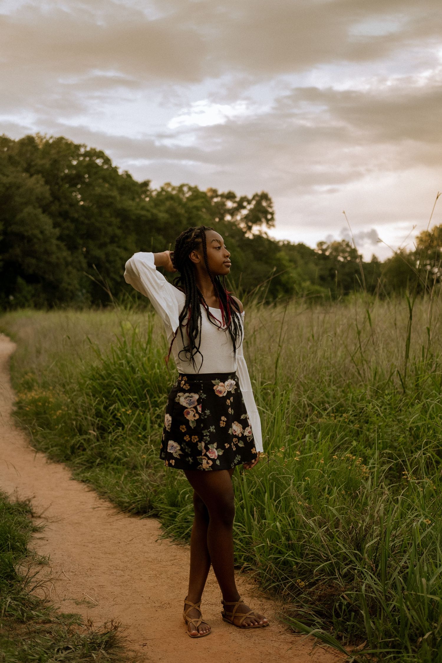 Photo of a senior girl standing in a field at golden hour