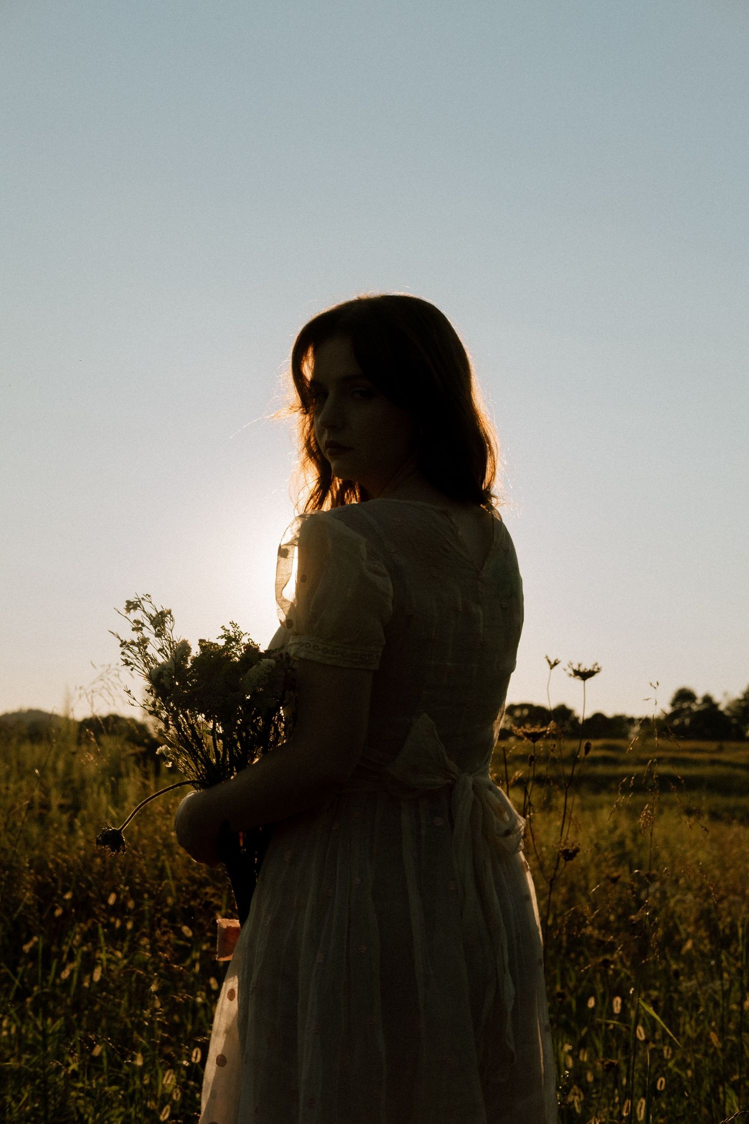 Photo of two girls in a field wearing a vintage dress at golden hour