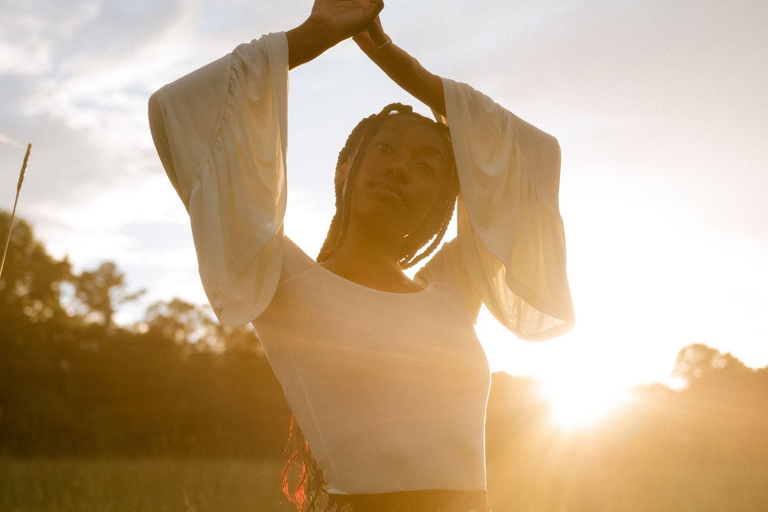 Photo of a senior girl with her arms above her head surrounded by sunlight