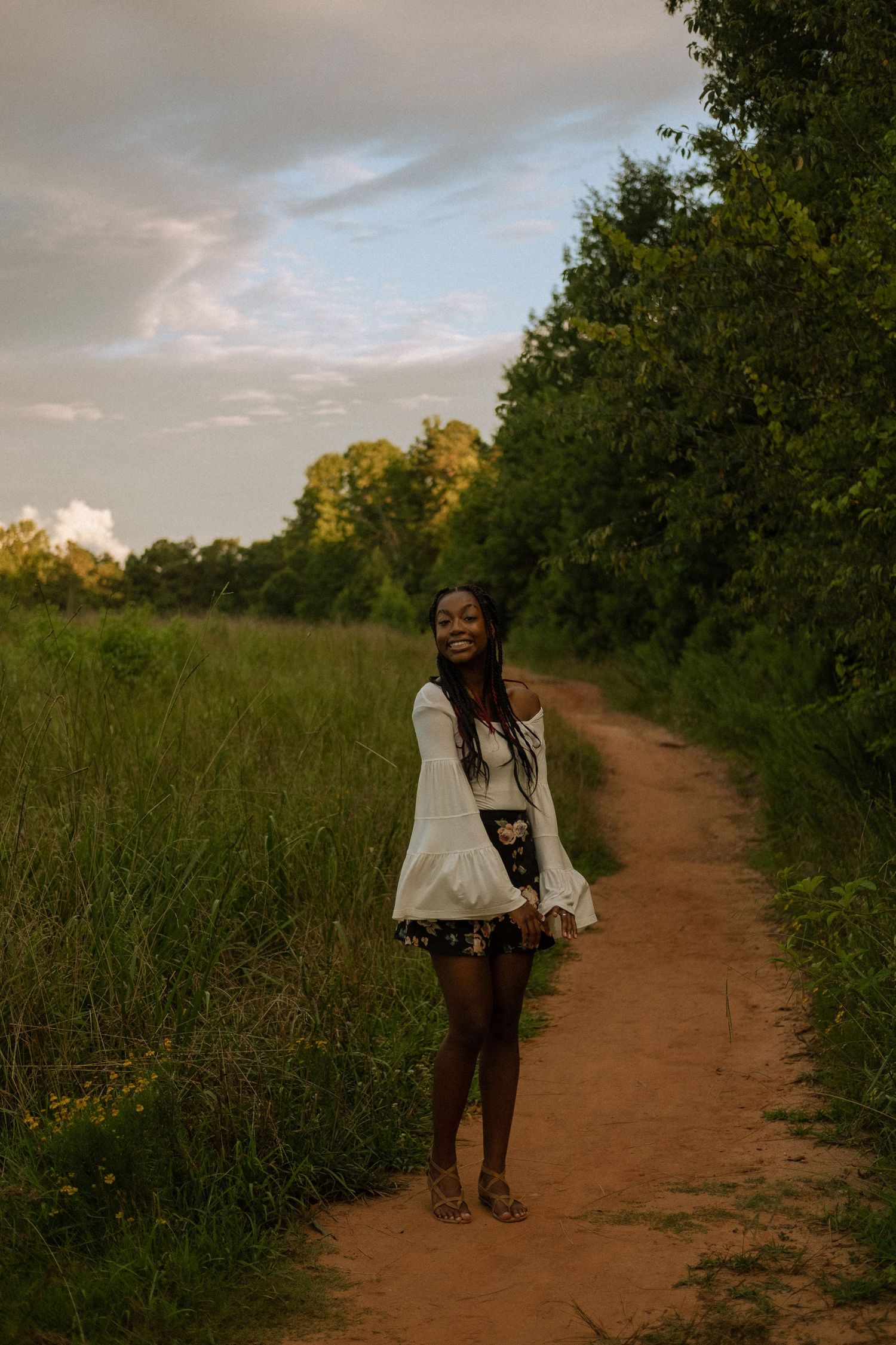 Photo of a senior girl standing in a field at golden hour