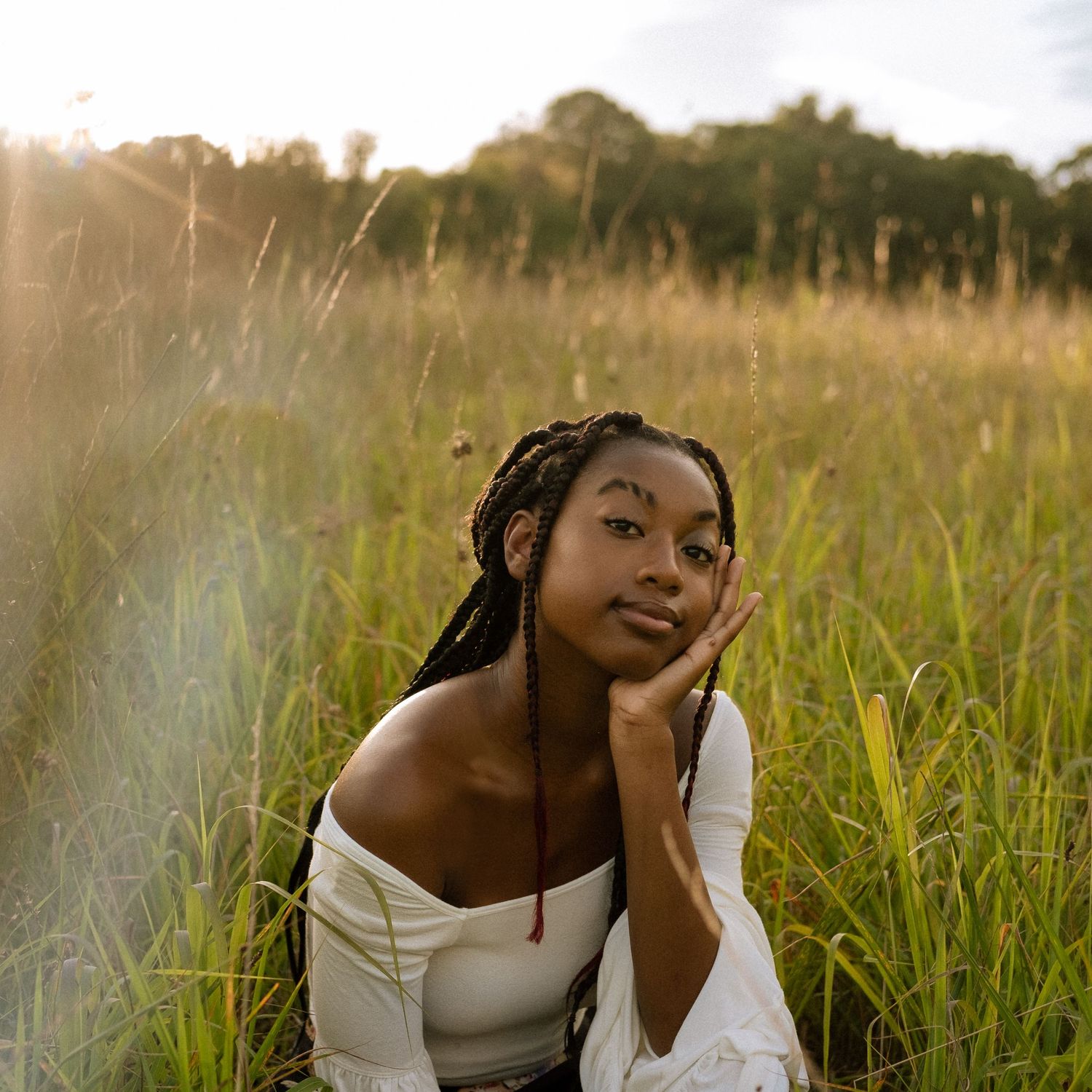 Photo of a senior girl in a field at golden hour with prism effects