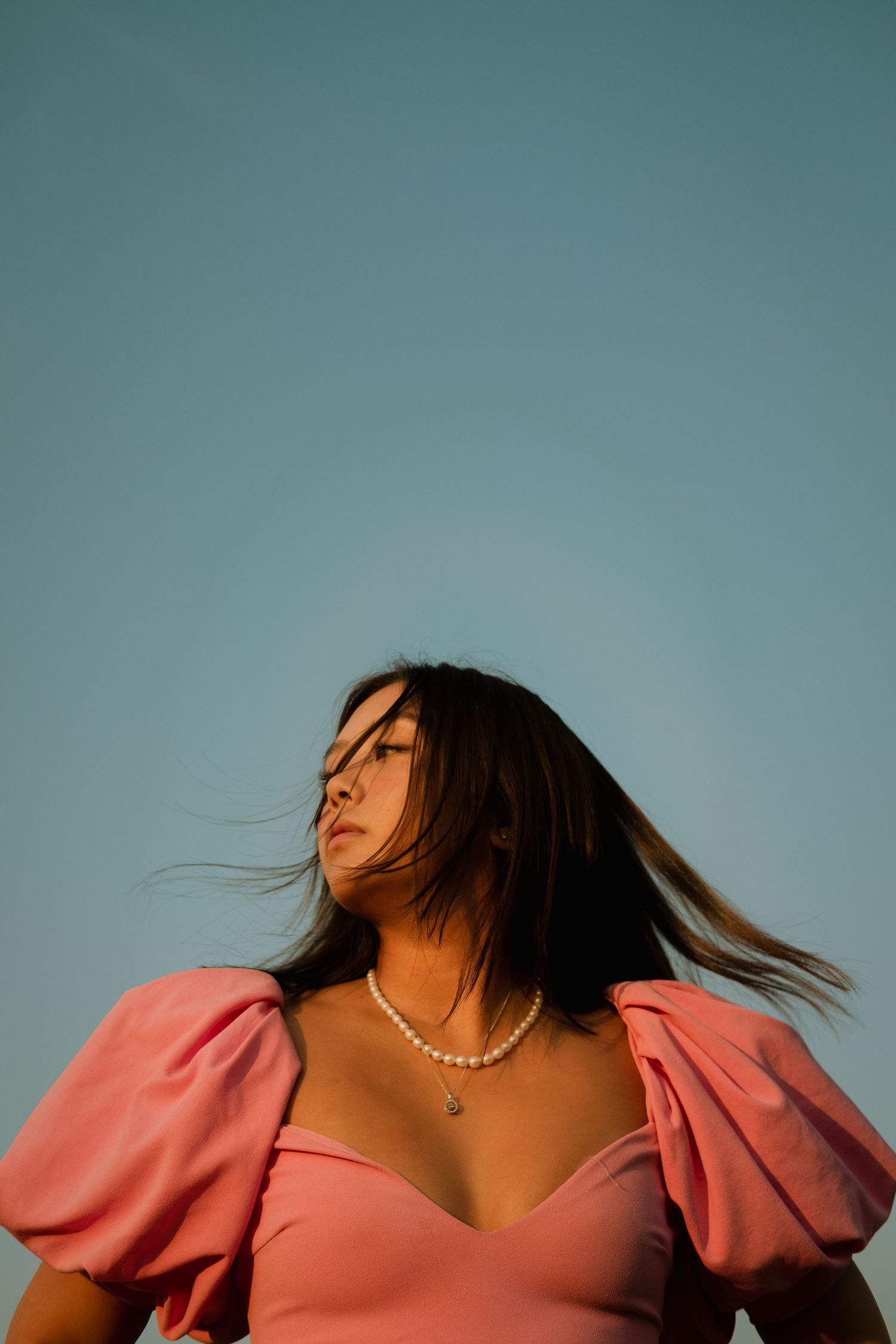 Girl in pink dress in front of blue sky