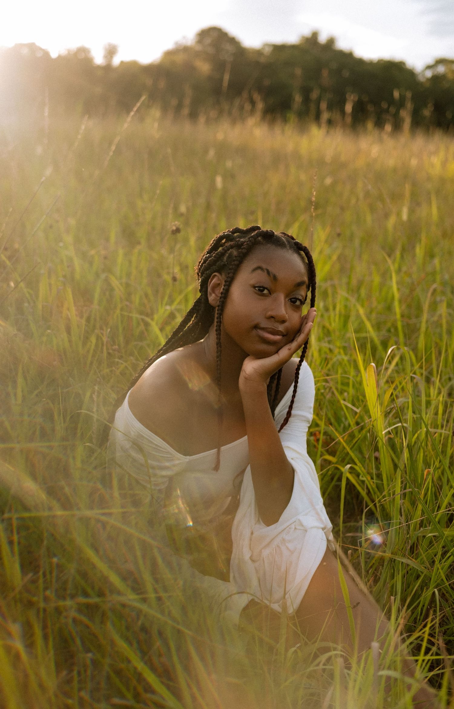 Photo of a senior girl in a field at golden hour with prism effects