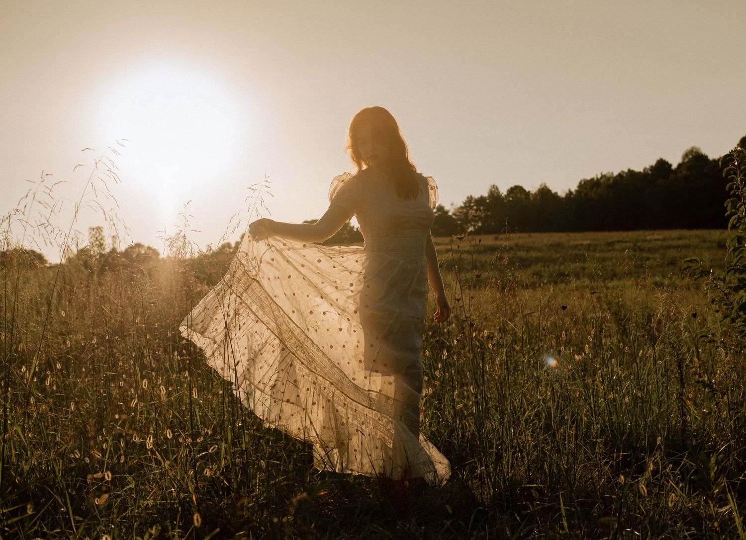 Photo of two girls in a field wearing a vintage dress at golden hour