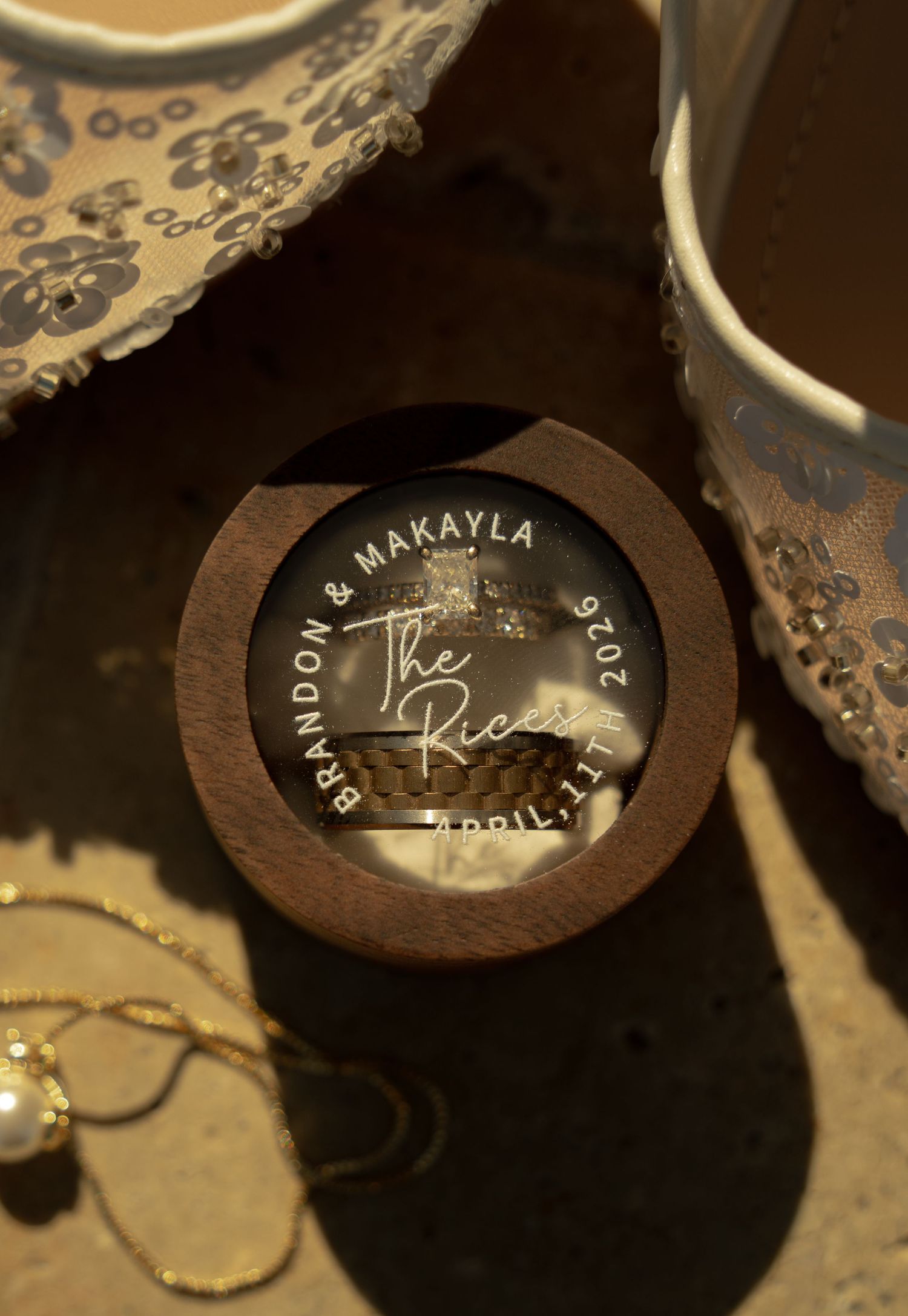 Custom wooden ring box engraved with Brandon & Makayla The Rices April 11, 2020 wedding date, holding two rings.