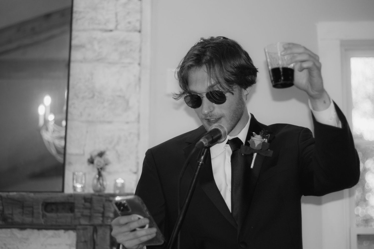 Person in formal attire holding a glass and making a toast at an elegant event.