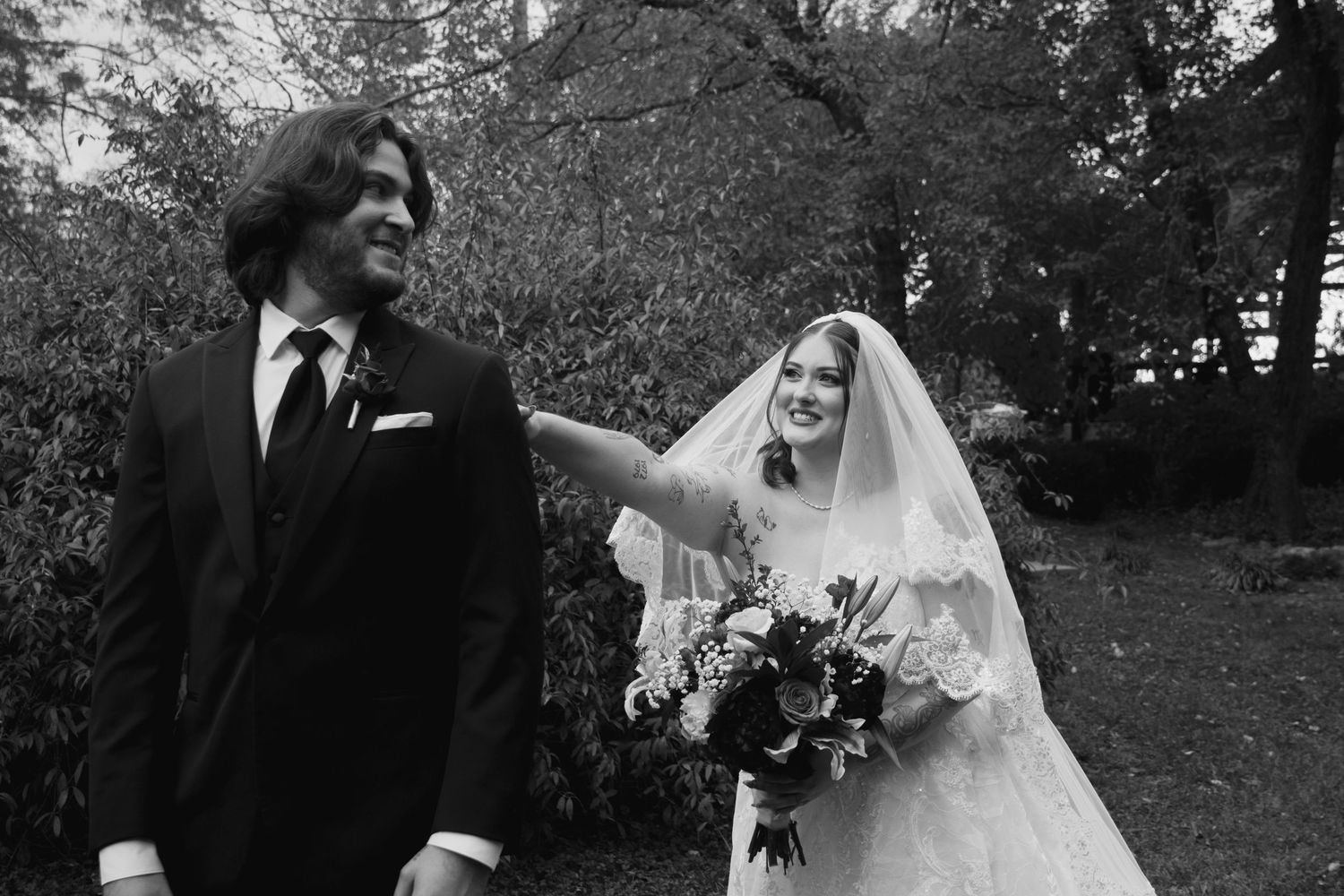 A bride and groom share an intimate moment together during their outdoor wedding photoshoot in a garden setting.