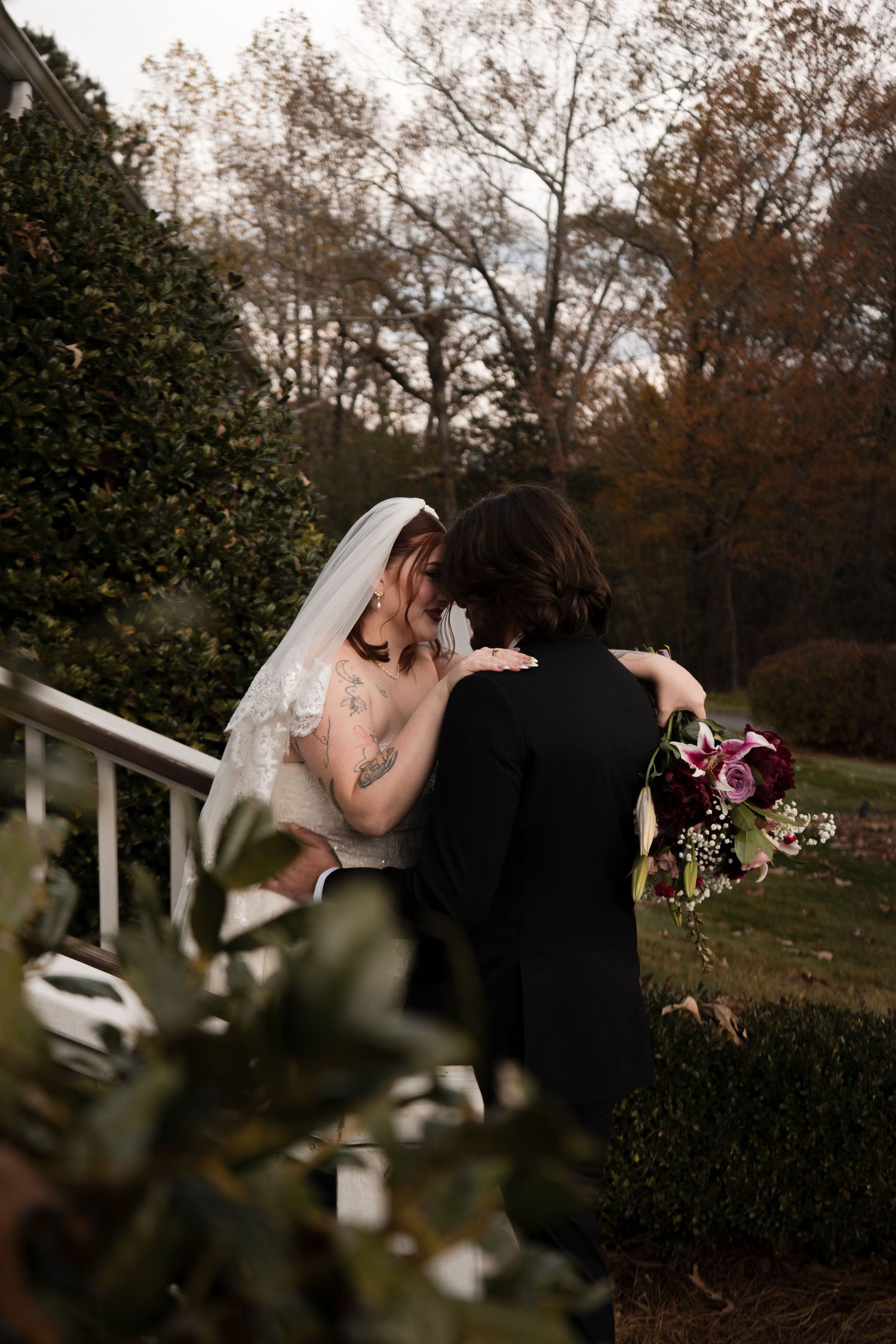A romantic wedding couple embraces in a scenic outdoor garden setting during autumn.