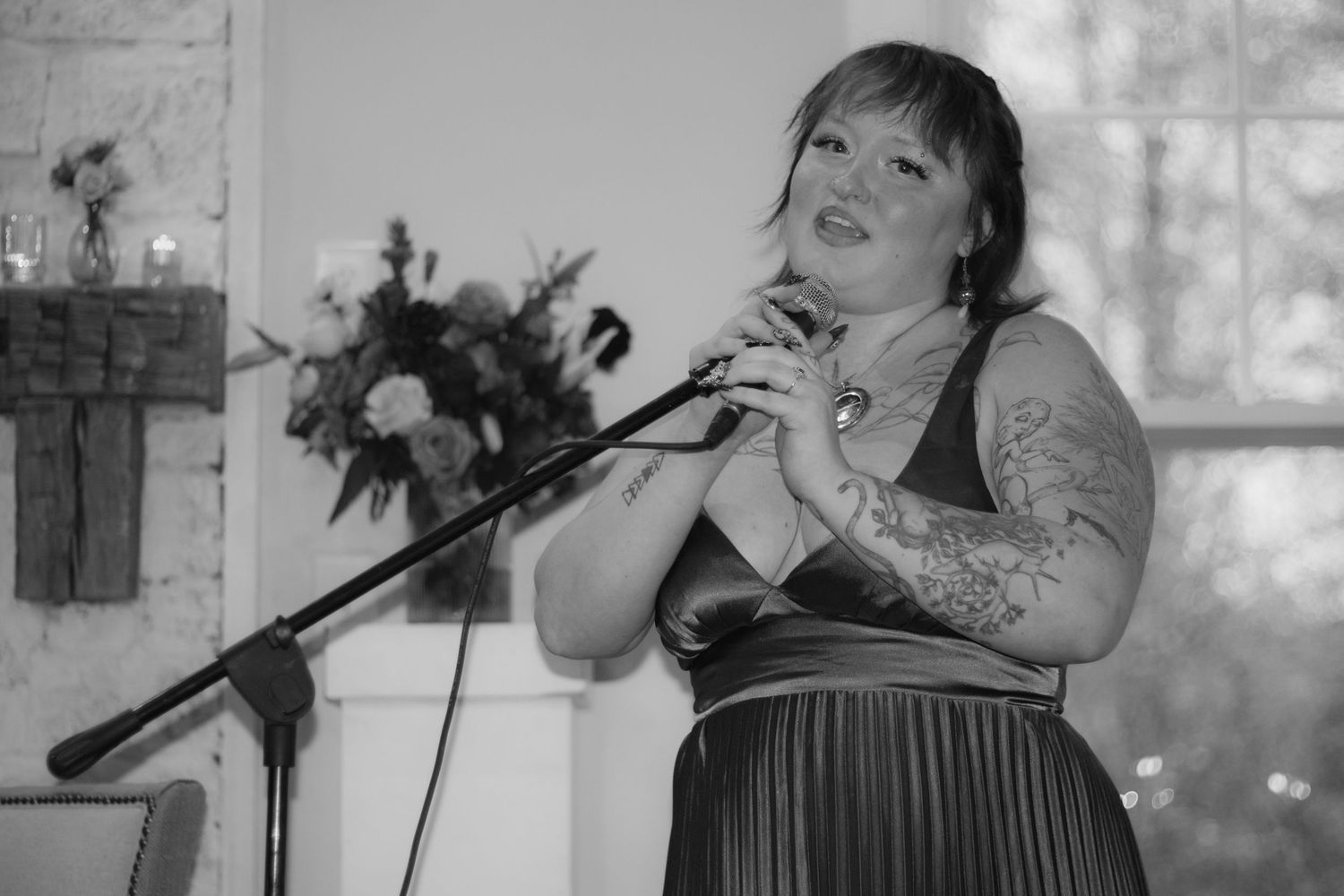 A performer sings passionately into a microphone on stage during a live performance with dramatic lighting.