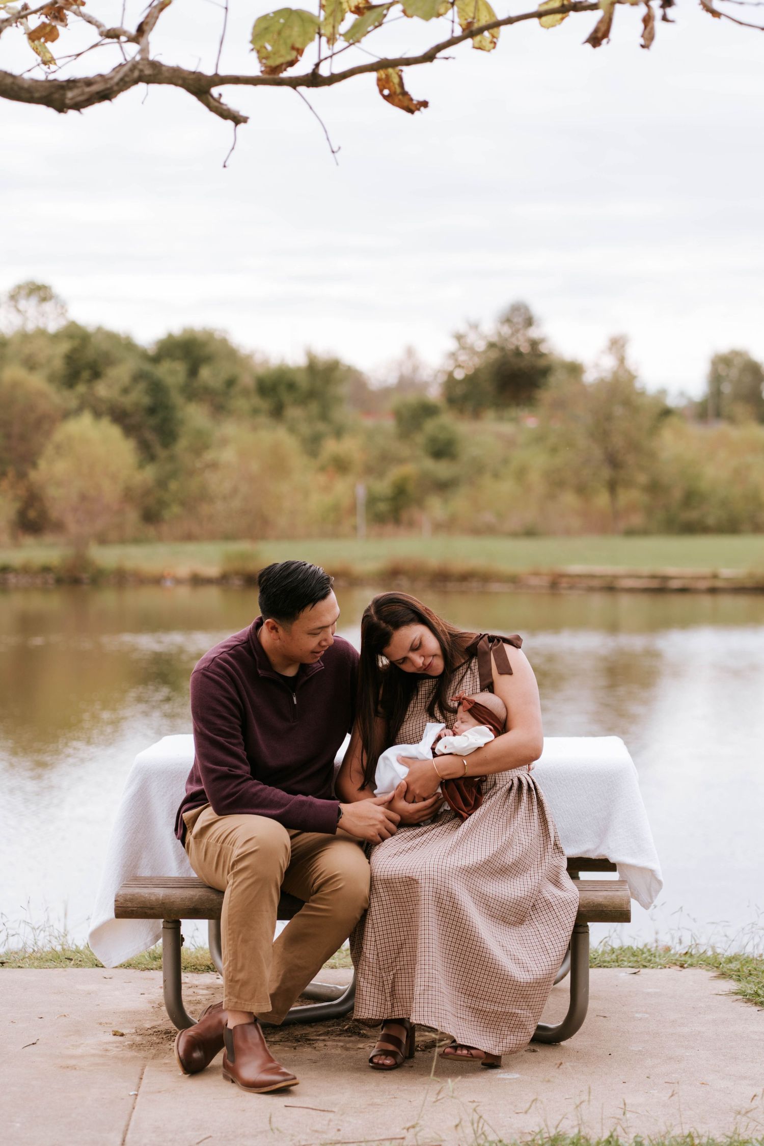 A couple shares an intimate moment while sitting together by a serene lake on a peaceful autumn day.