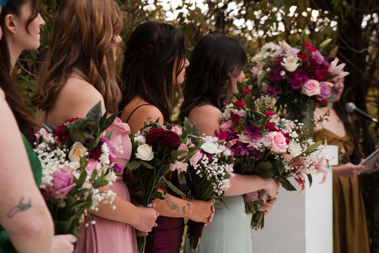 Wedding party holding vibrant pink and purple floral bouquets.