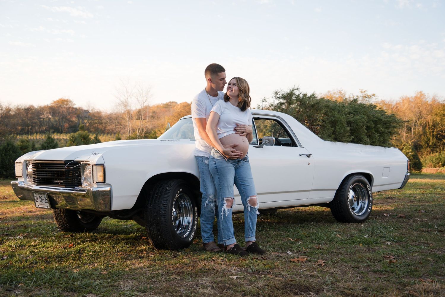 A classic white car serves as a backdrop for an intimate couple's portrait session at golden hour.